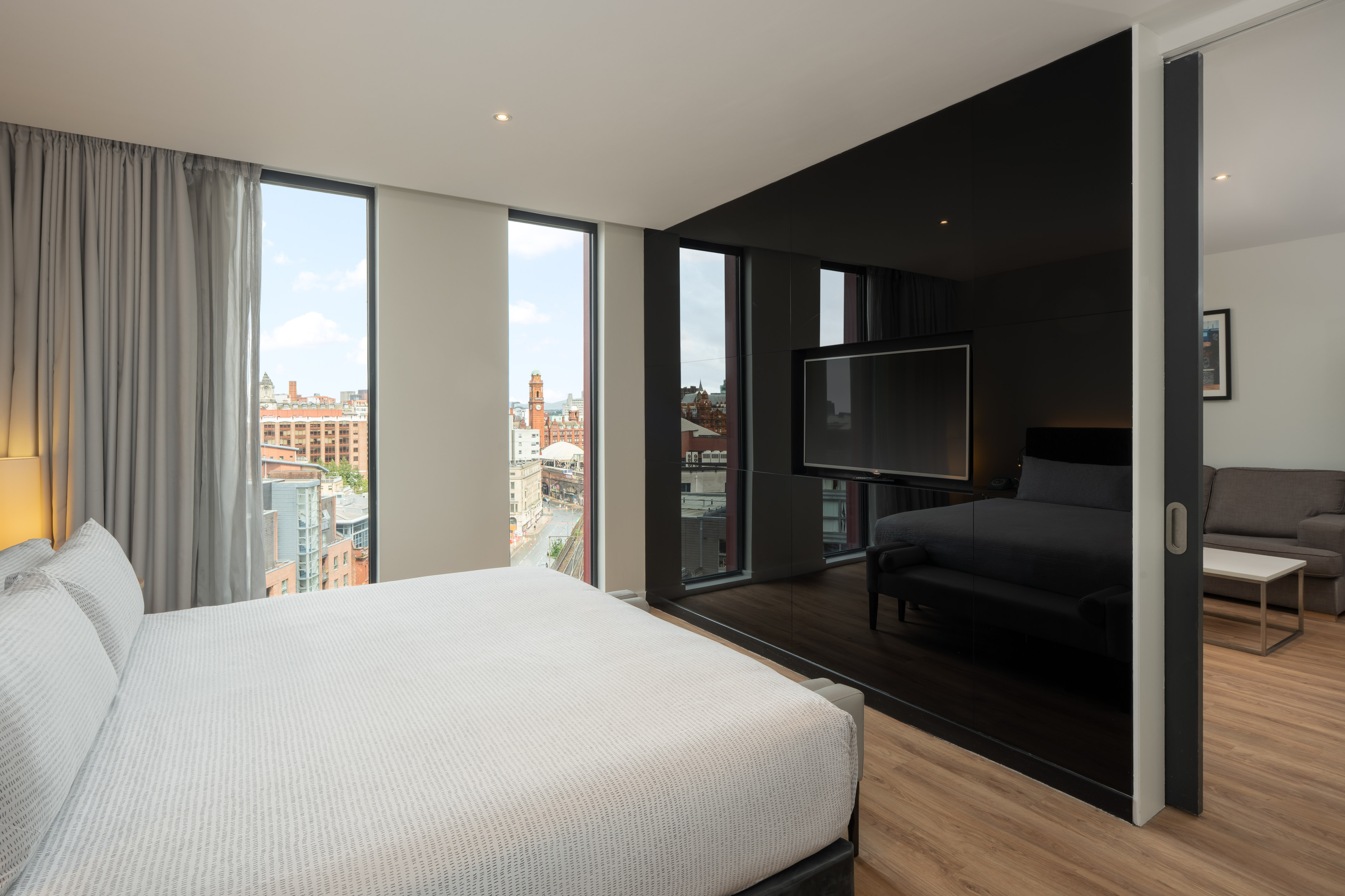 Modern hotel suite with city view, king bed, and separated living space.