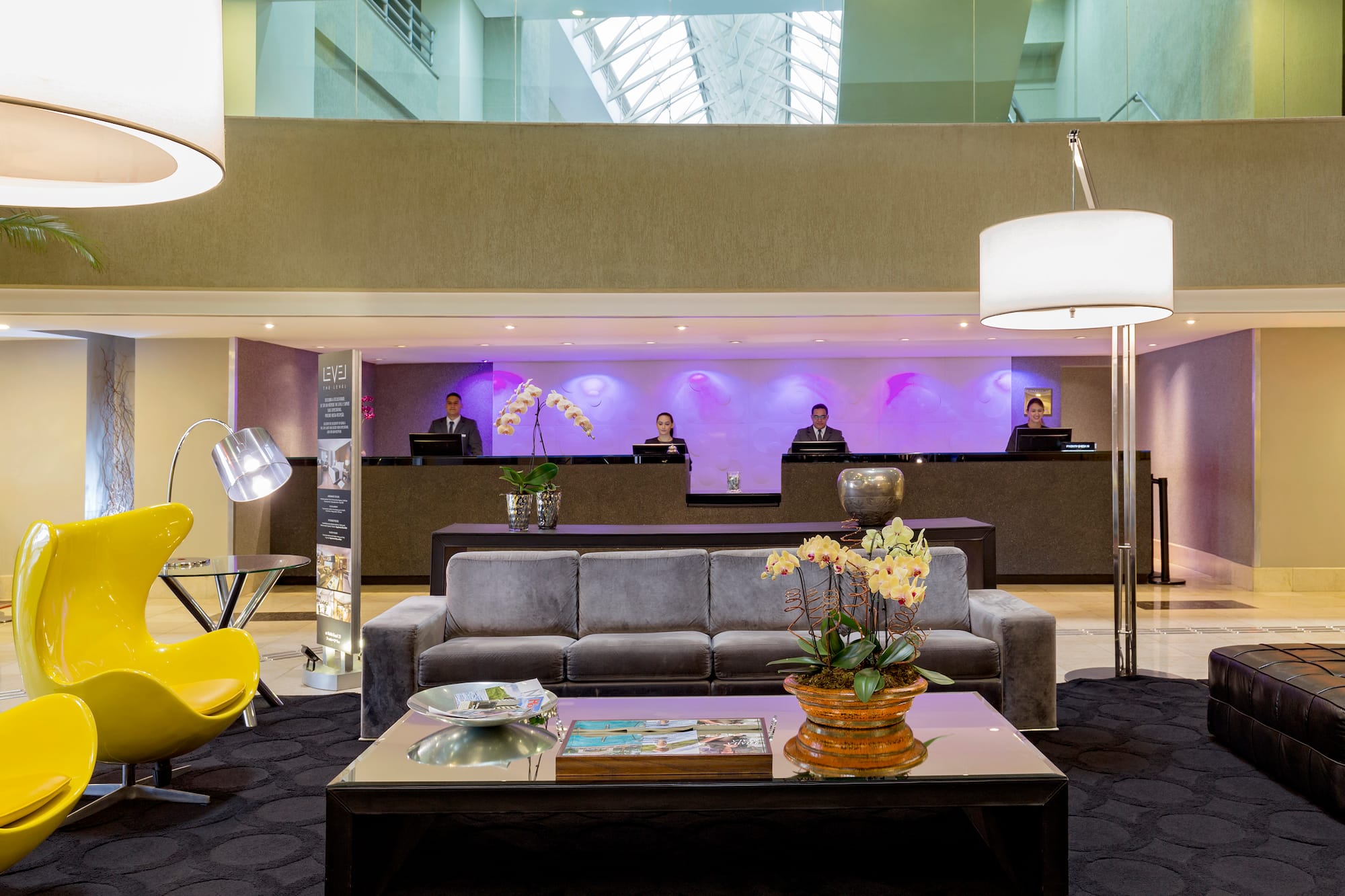a lobby with a couch and a table with a lamp and people behind it