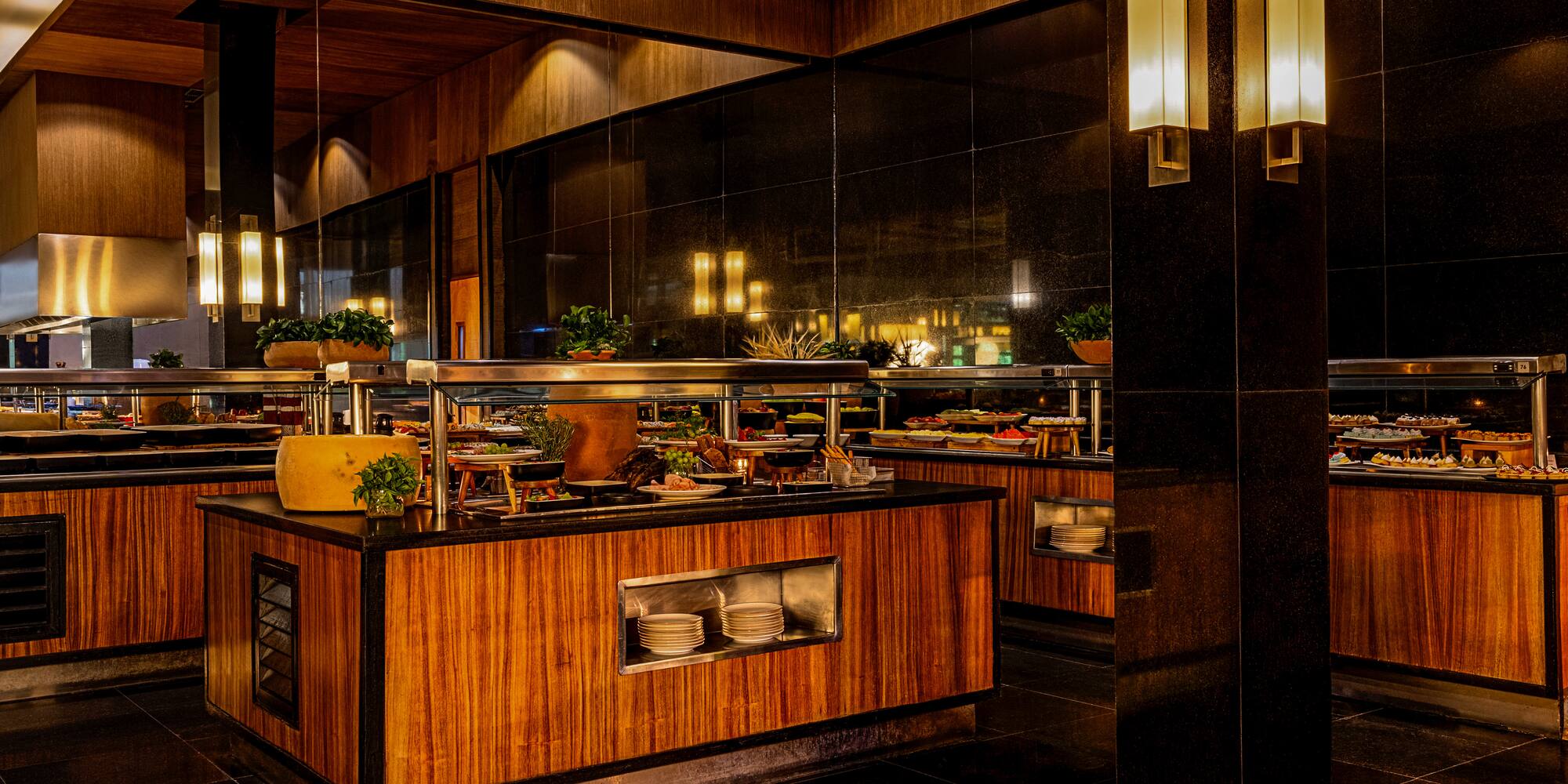 Elegant restaurant buffet with various food, dark wood, and warm lighting.