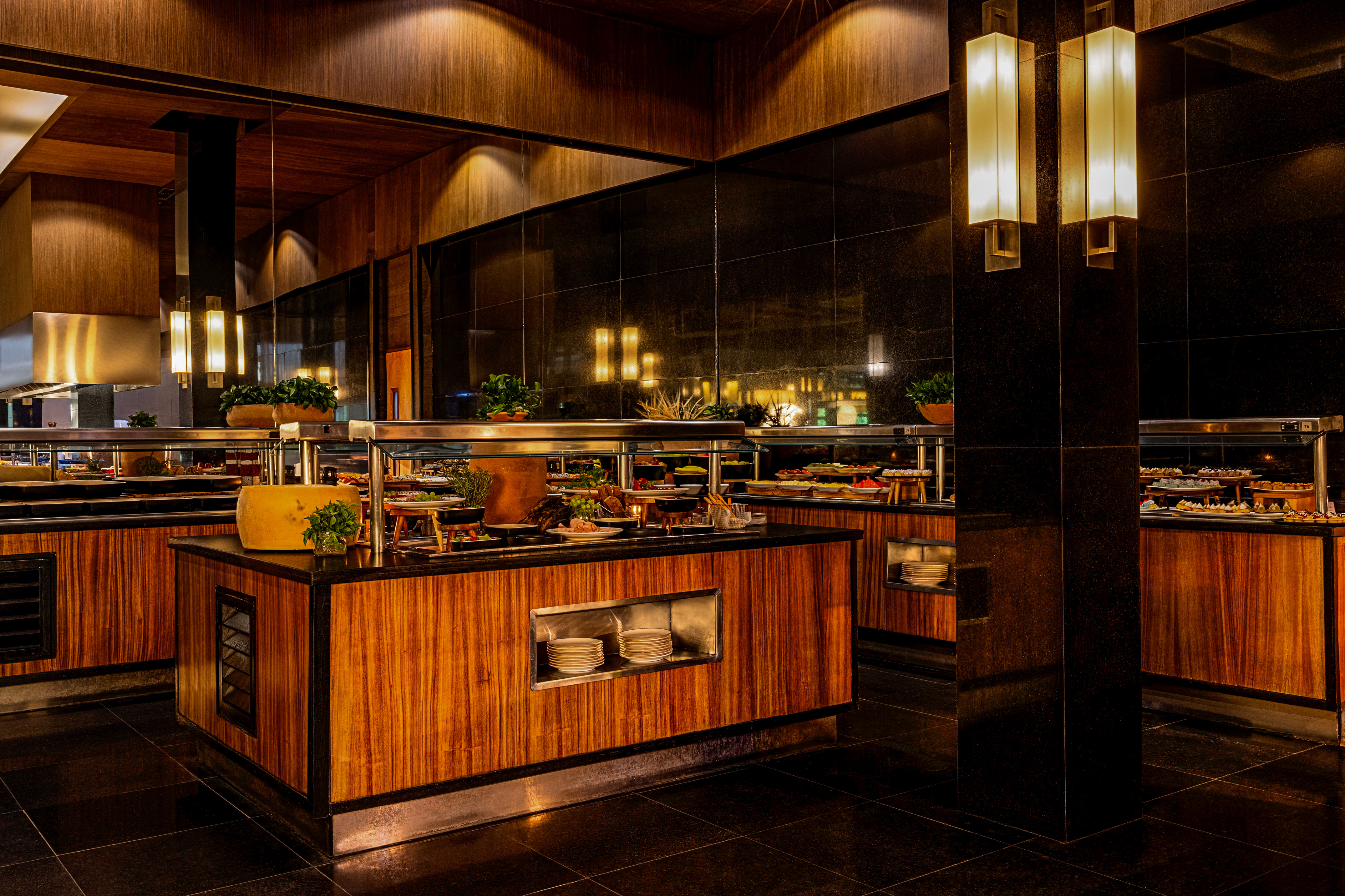 Elegant restaurant buffet with various food, dark wood, and warm lighting.