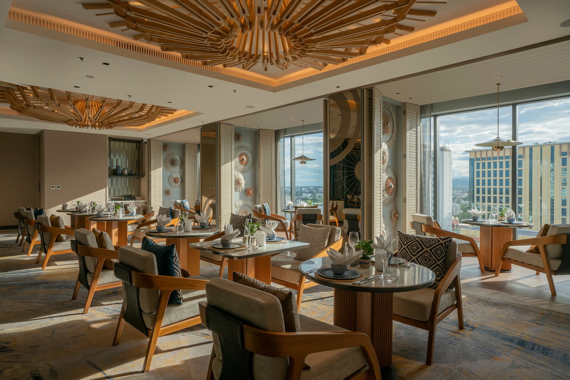Upscale restaurant with modern wood ceiling, city views, and set dining tables.