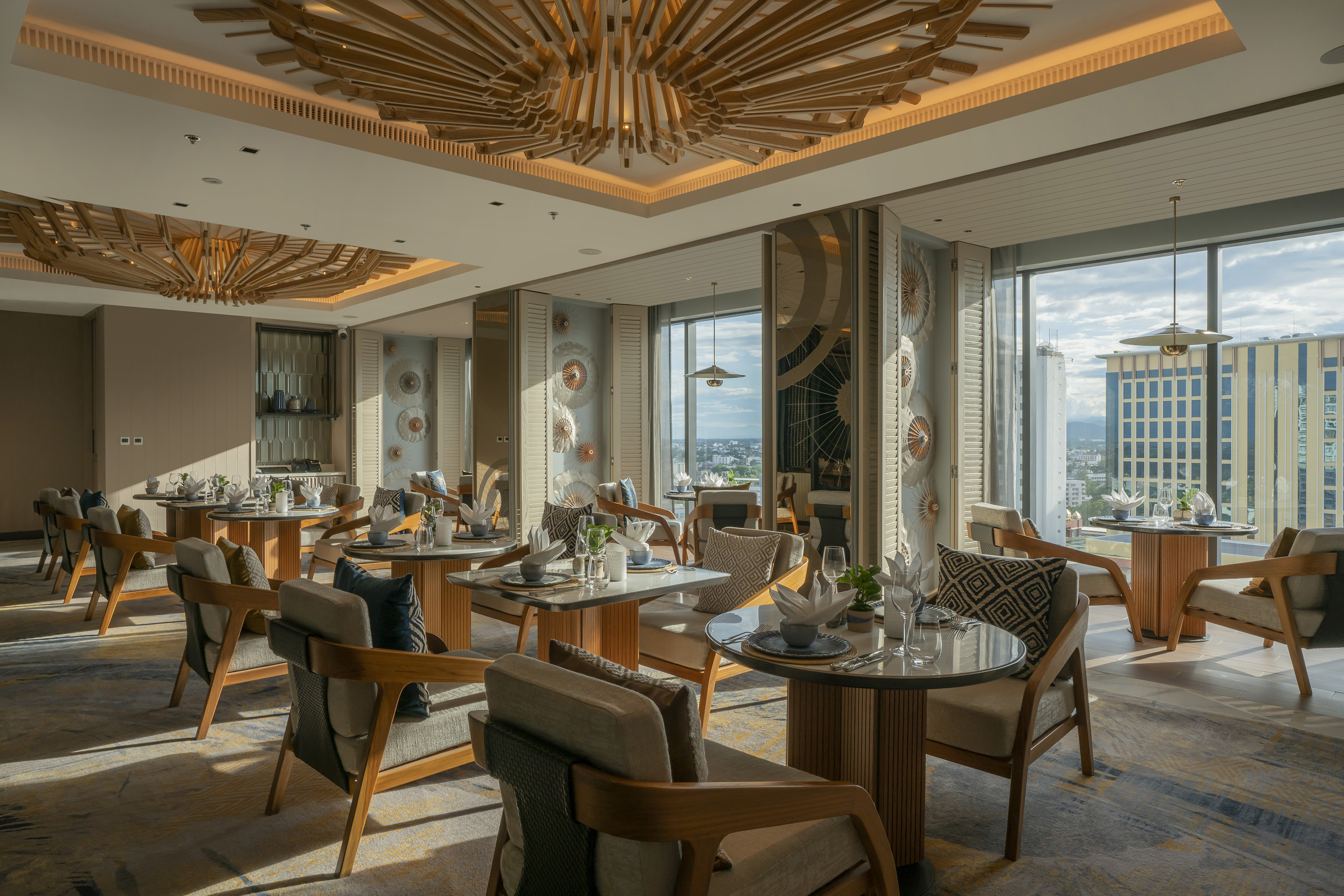 Upscale restaurant with modern wood ceiling, city views, and set dining tables.