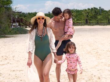 a man and woman holding two children on a beach