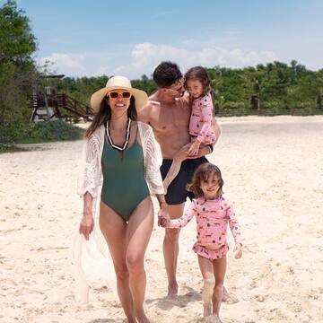 a man and woman holding two children on a beach