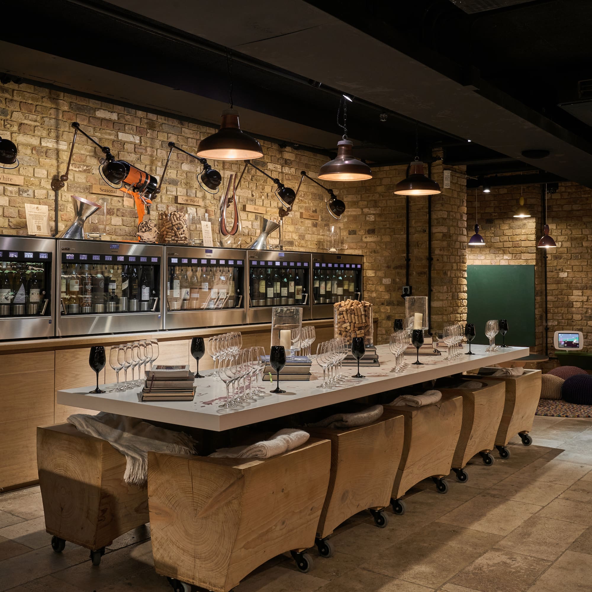 a long table with wine glasses and chairs in a room with brick walls