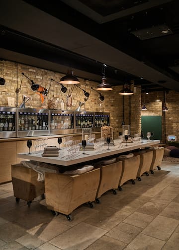 a long table with wine glasses and chairs in a room with brick walls