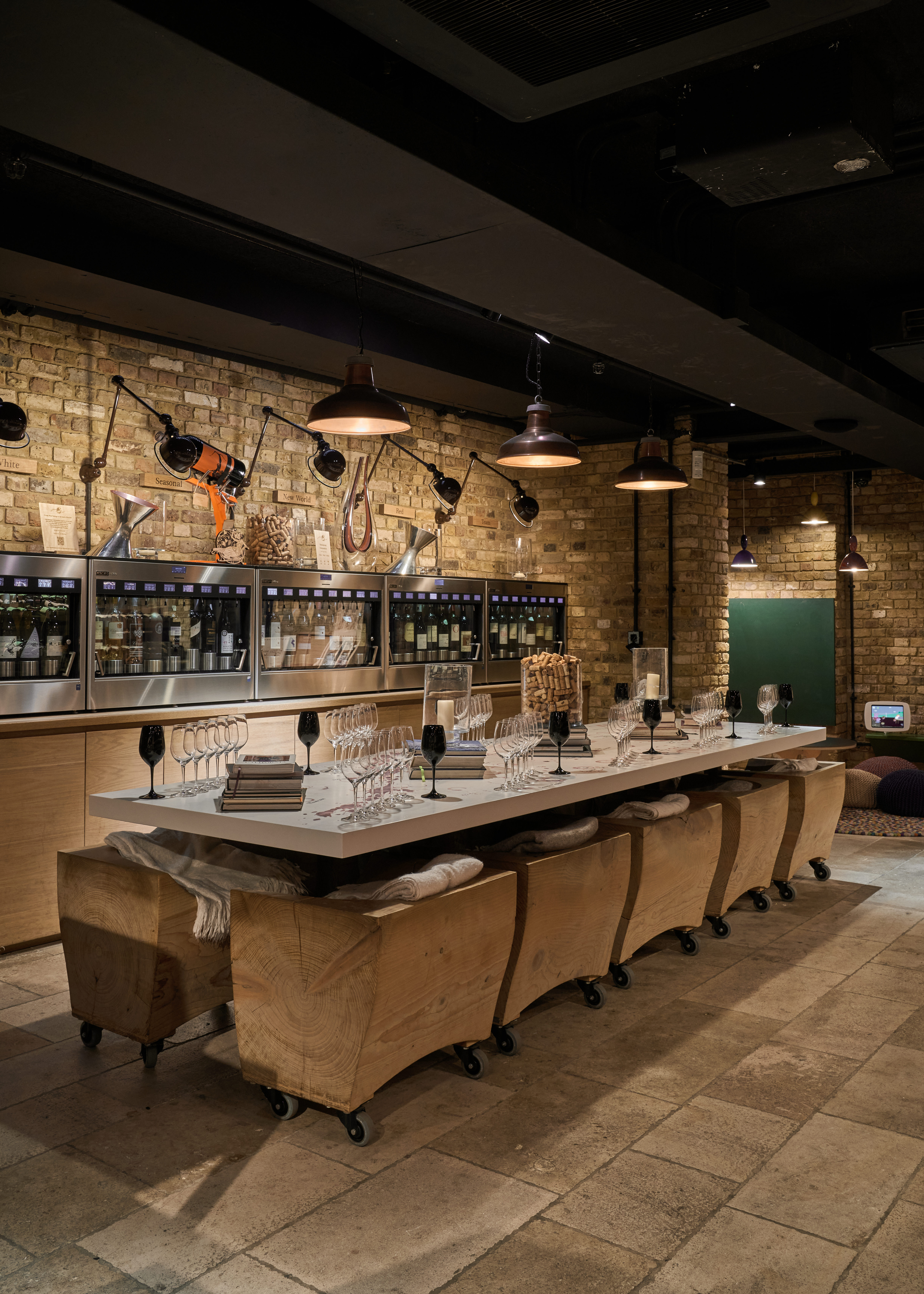 a long table with wine glasses and chairs in a room with brick walls