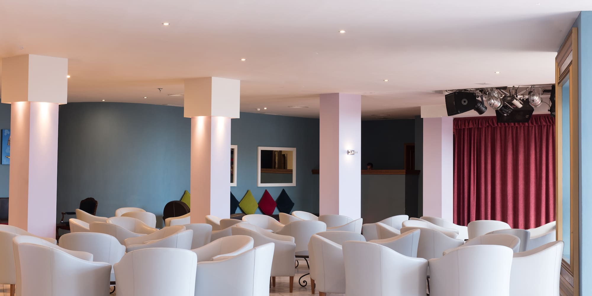 a room with white chairs and red curtains