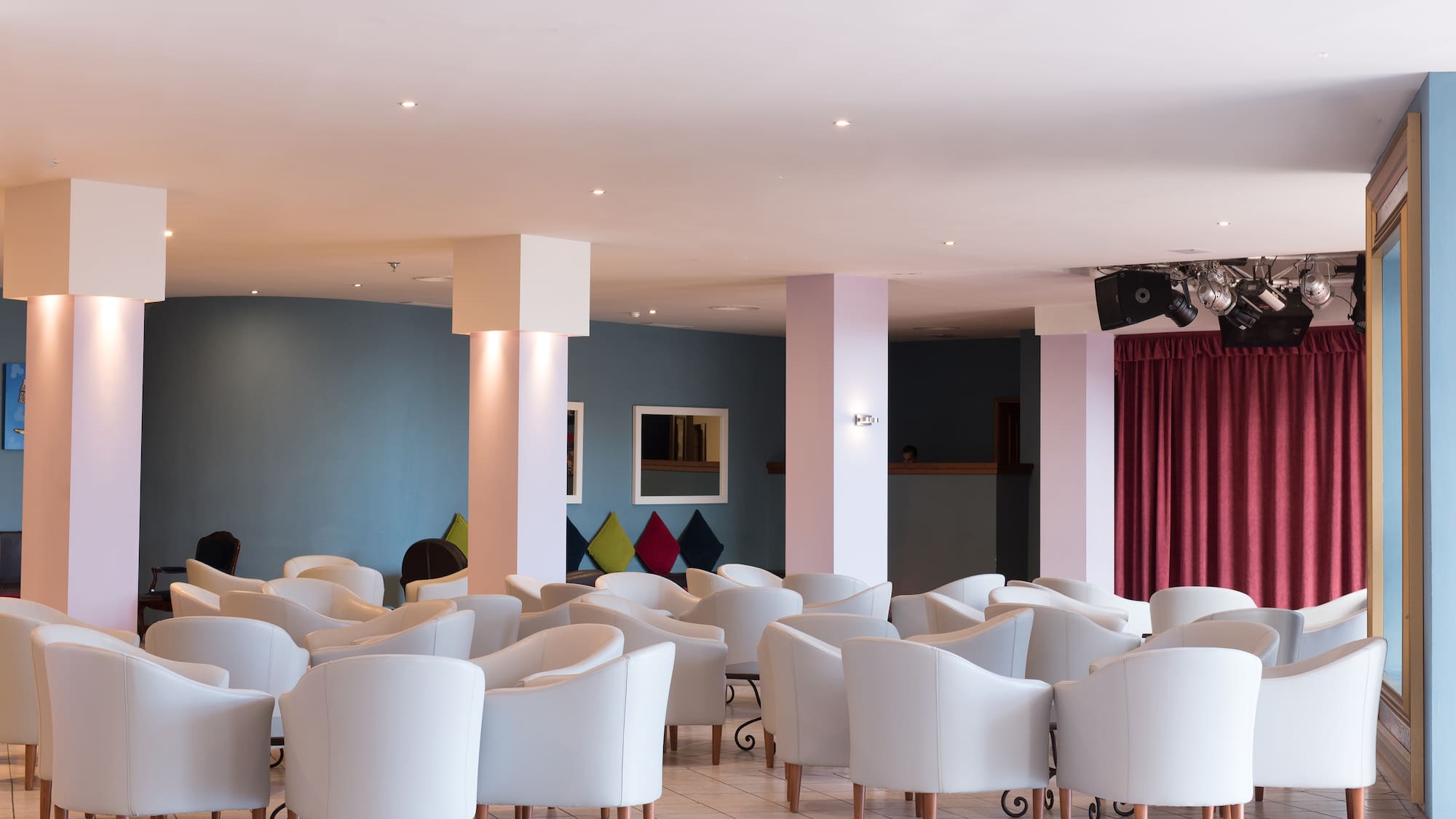 a room with white chairs and red curtains