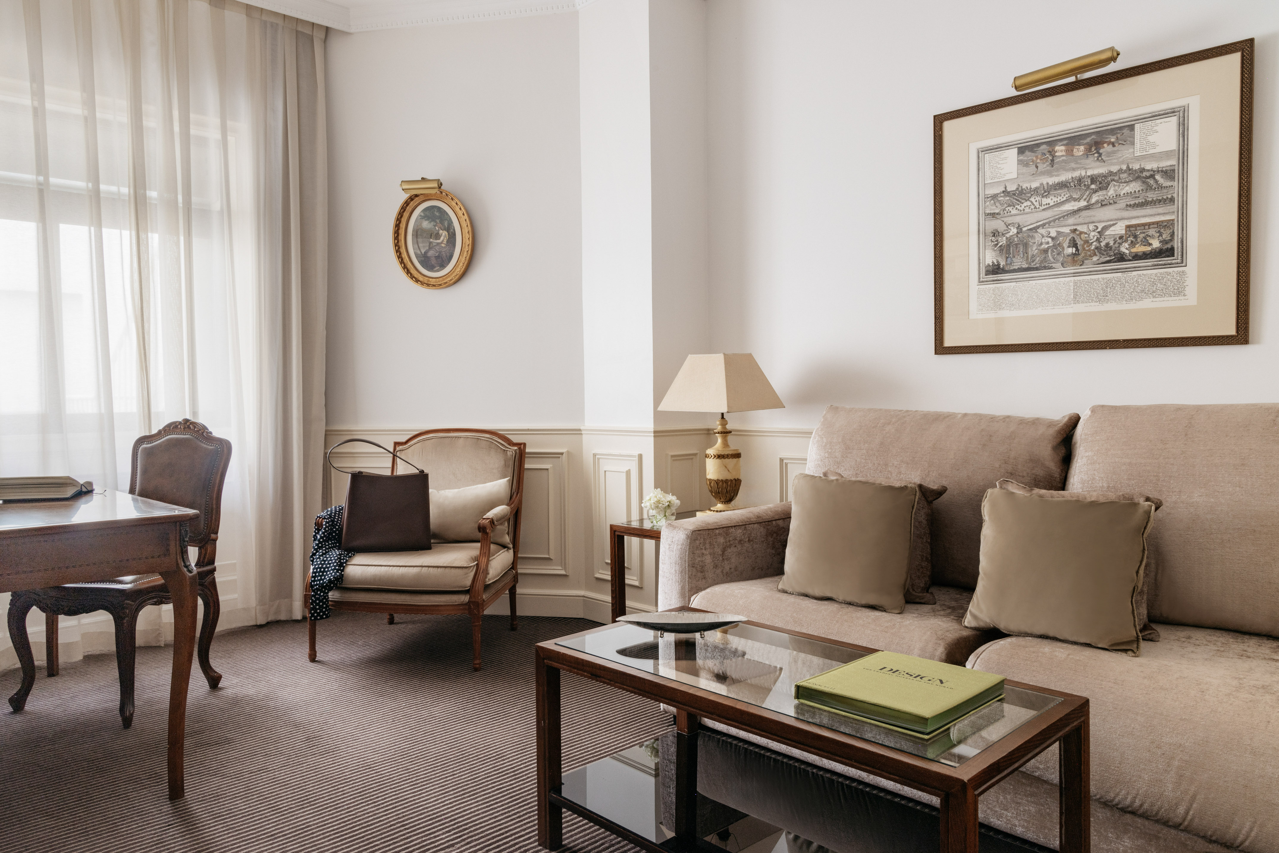 Elegant living room with sofa, armchair, coffee table, desk, and neutral decor.