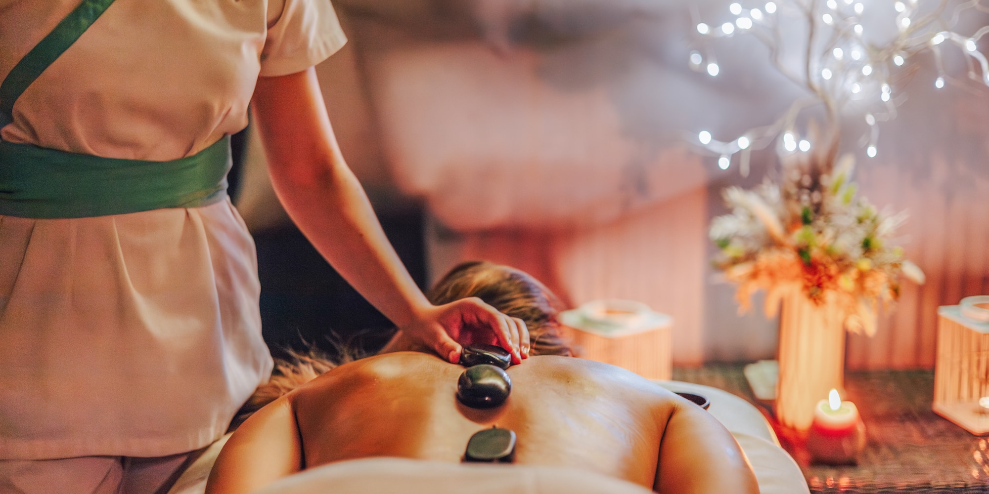 Therapist applies hot stones to client's back during a spa massage.