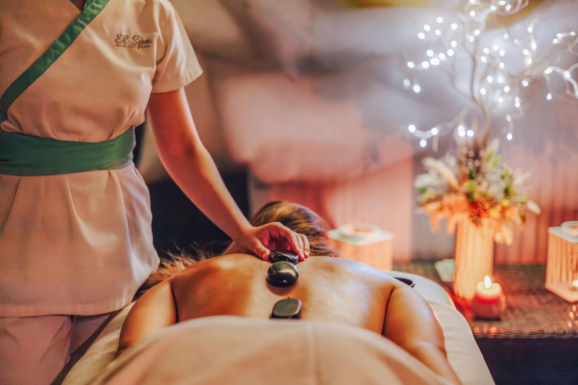 Therapist applies hot stones to client's back during a spa massage.