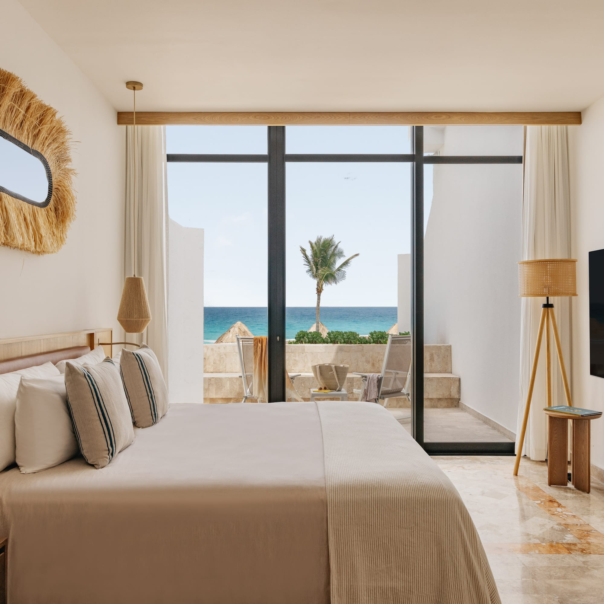 Ocean view bedroom with large bed, modern coastal decor, and balcony.