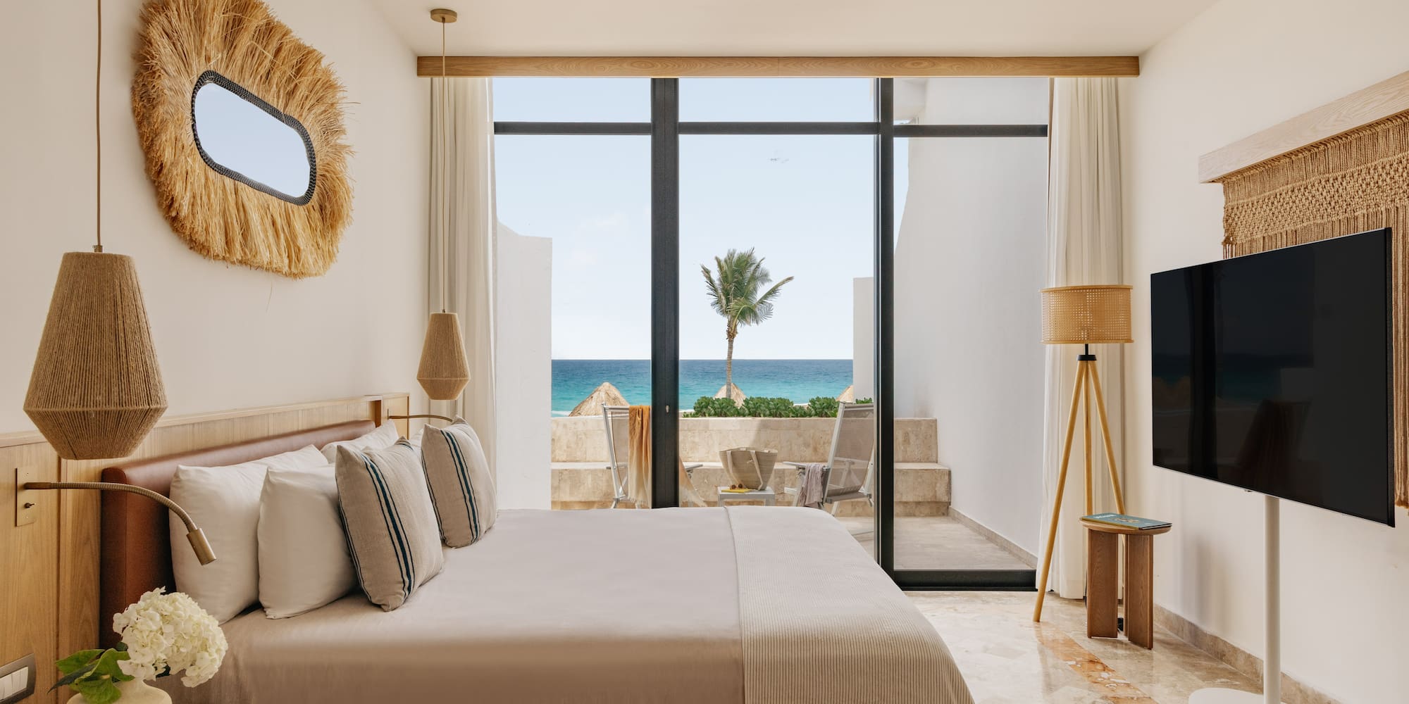 Ocean view bedroom with large bed, modern coastal decor, and balcony.