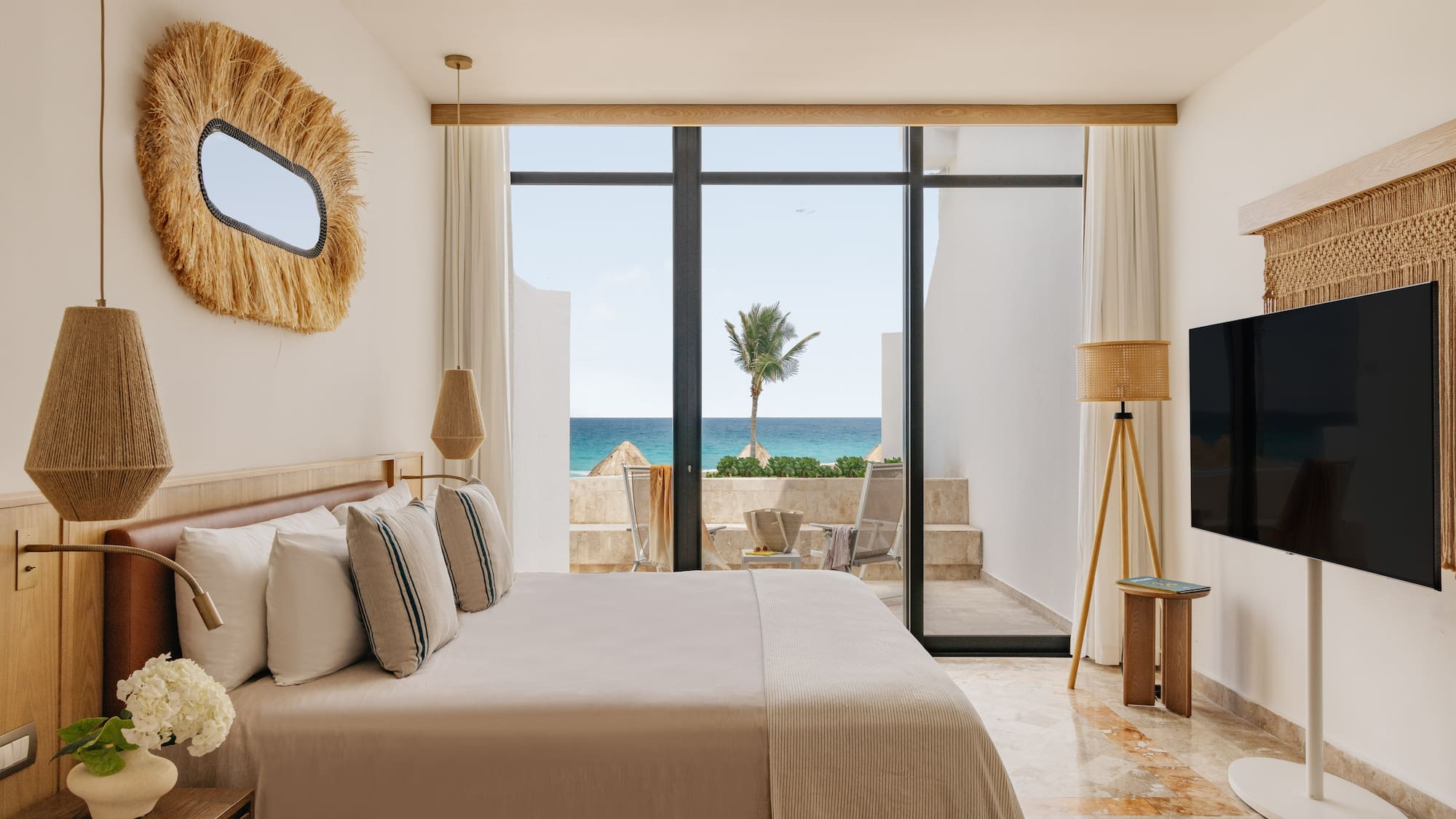 Ocean view bedroom with large bed, modern coastal decor, and balcony.