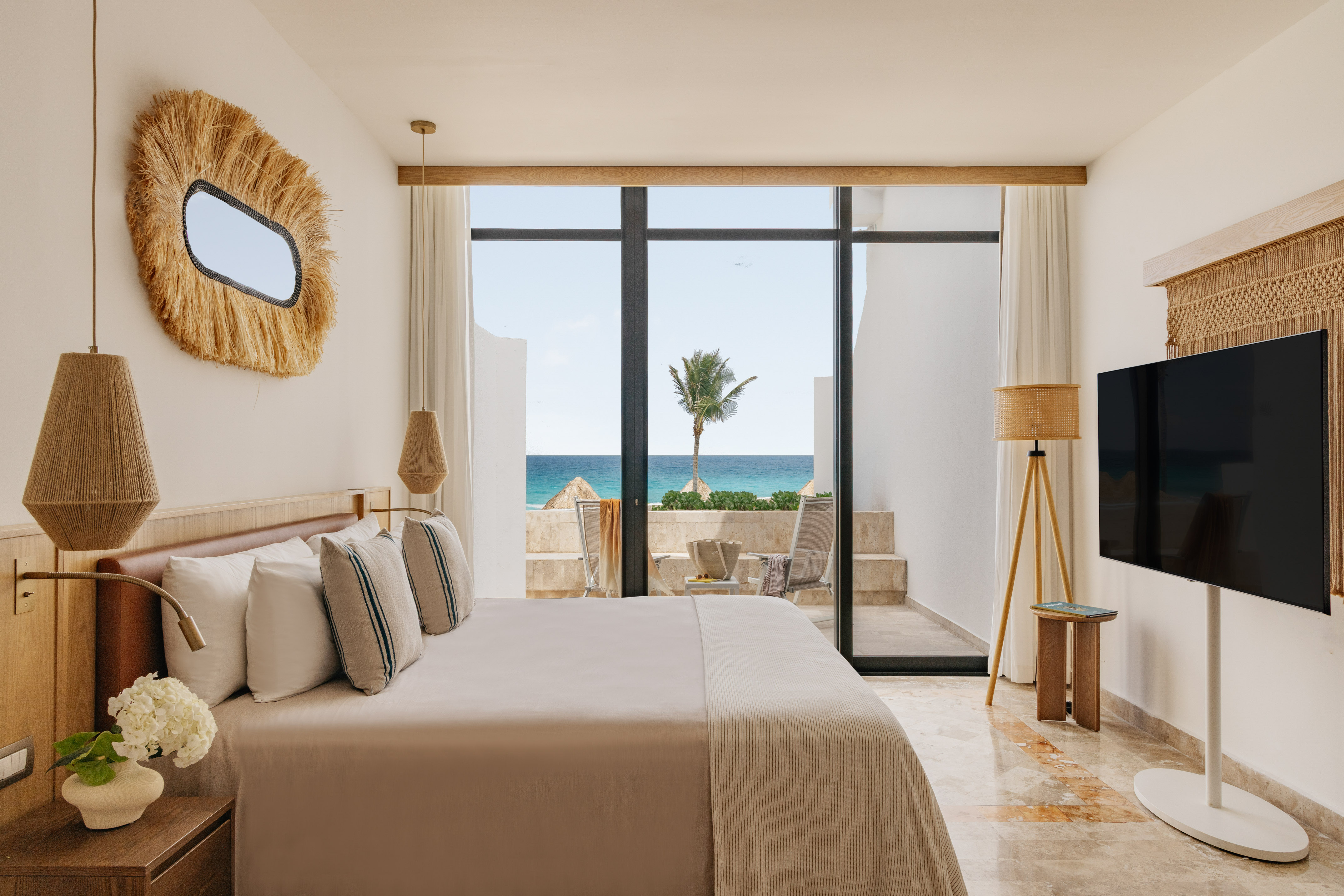 Ocean view bedroom with large bed, modern coastal decor, and balcony.