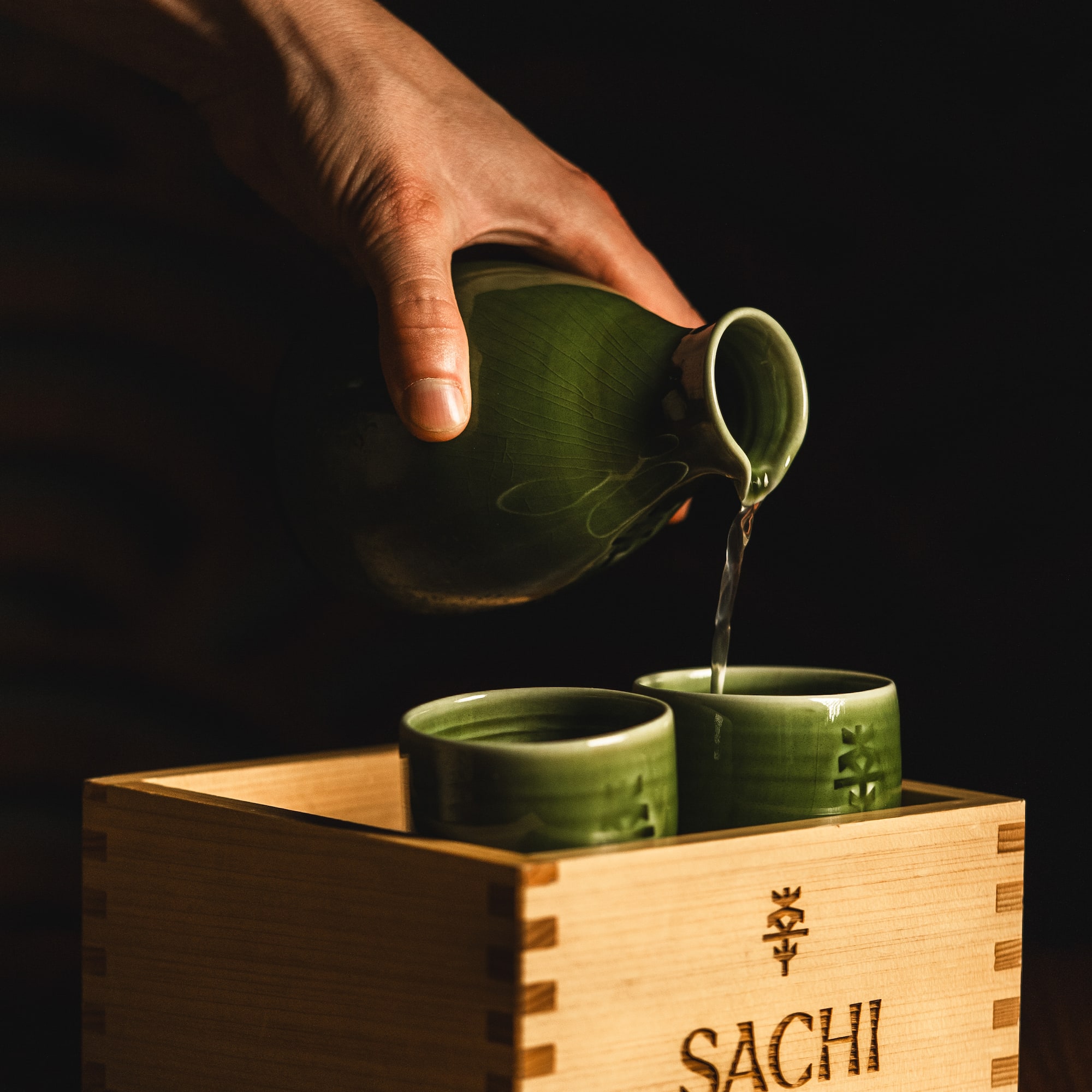 a person pouring liquid into cups
