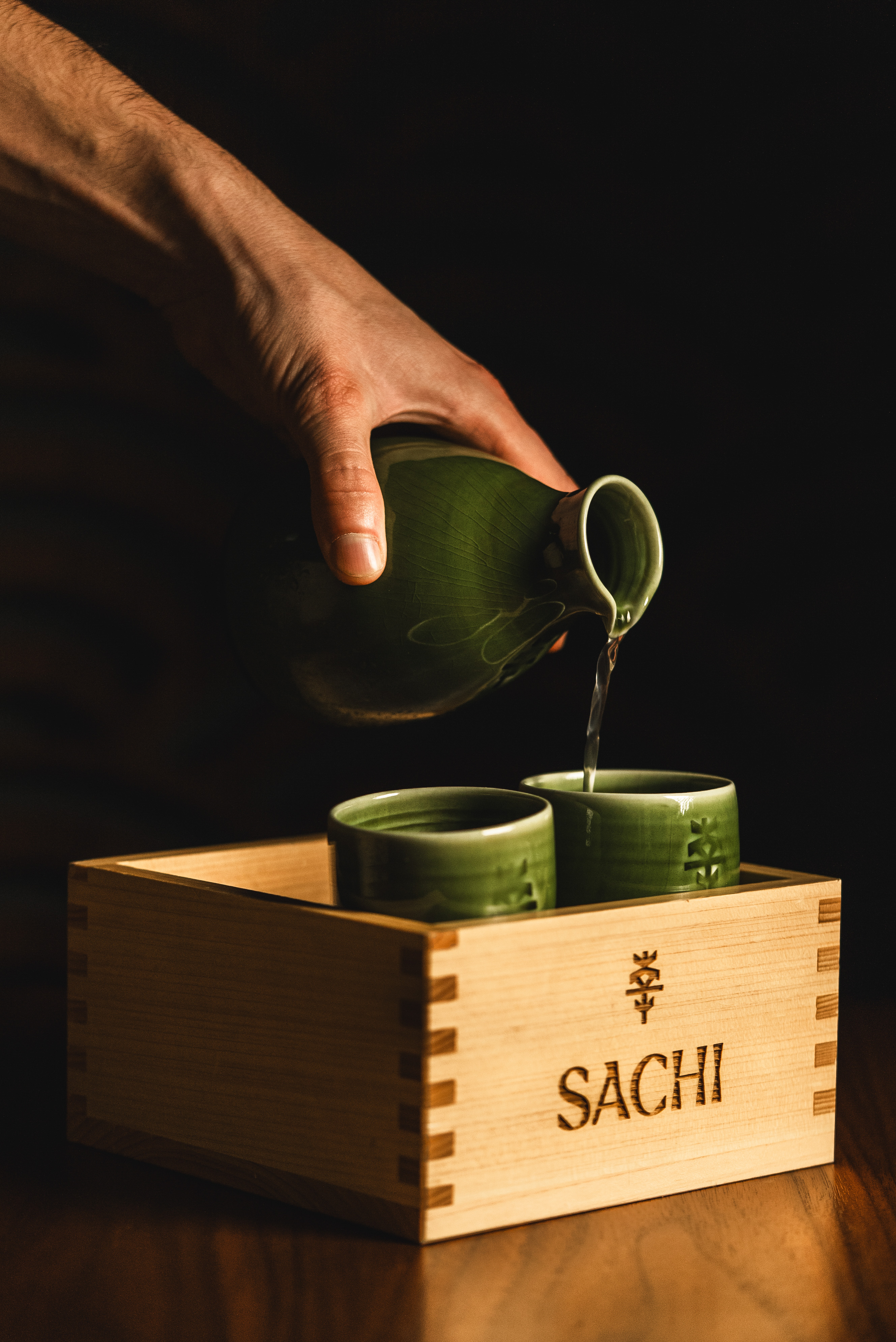 a person pouring liquid into cups