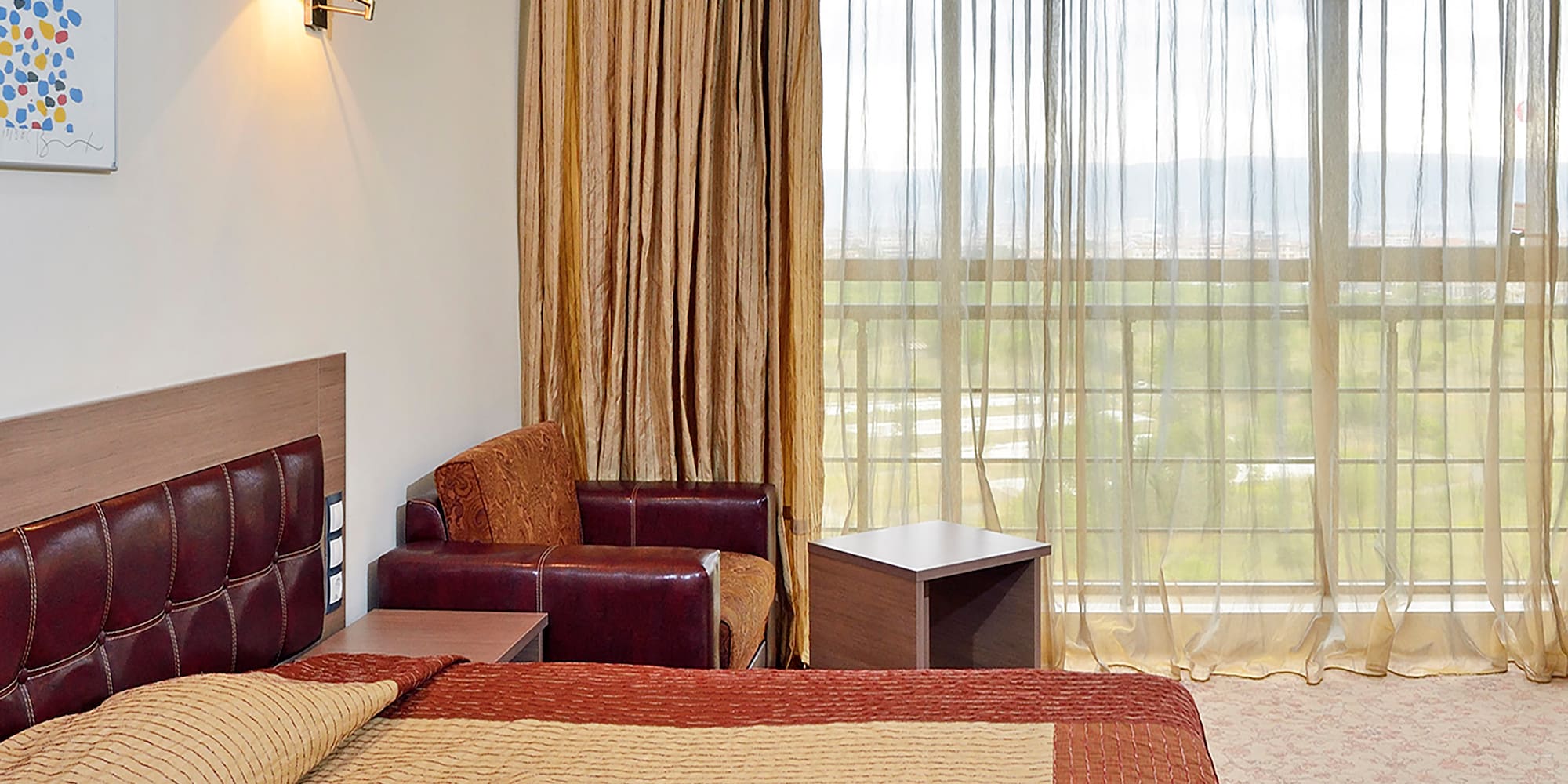 a bed with pillows and a chair in a room with curtains