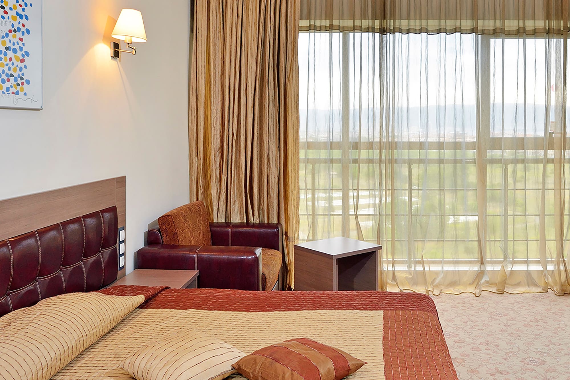 a bed with pillows and a chair in a room with curtains