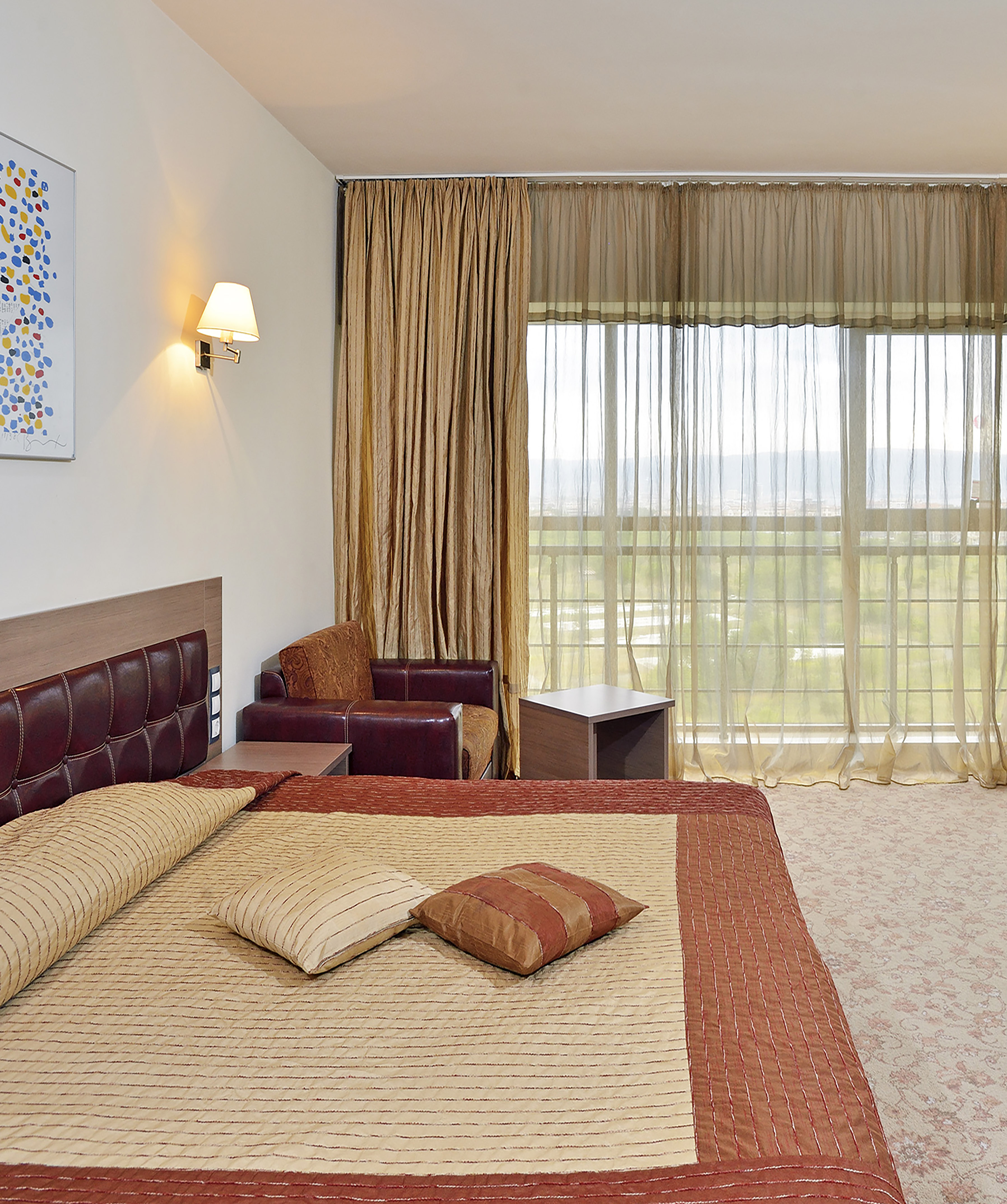 a bed with pillows and a chair in a room with curtains