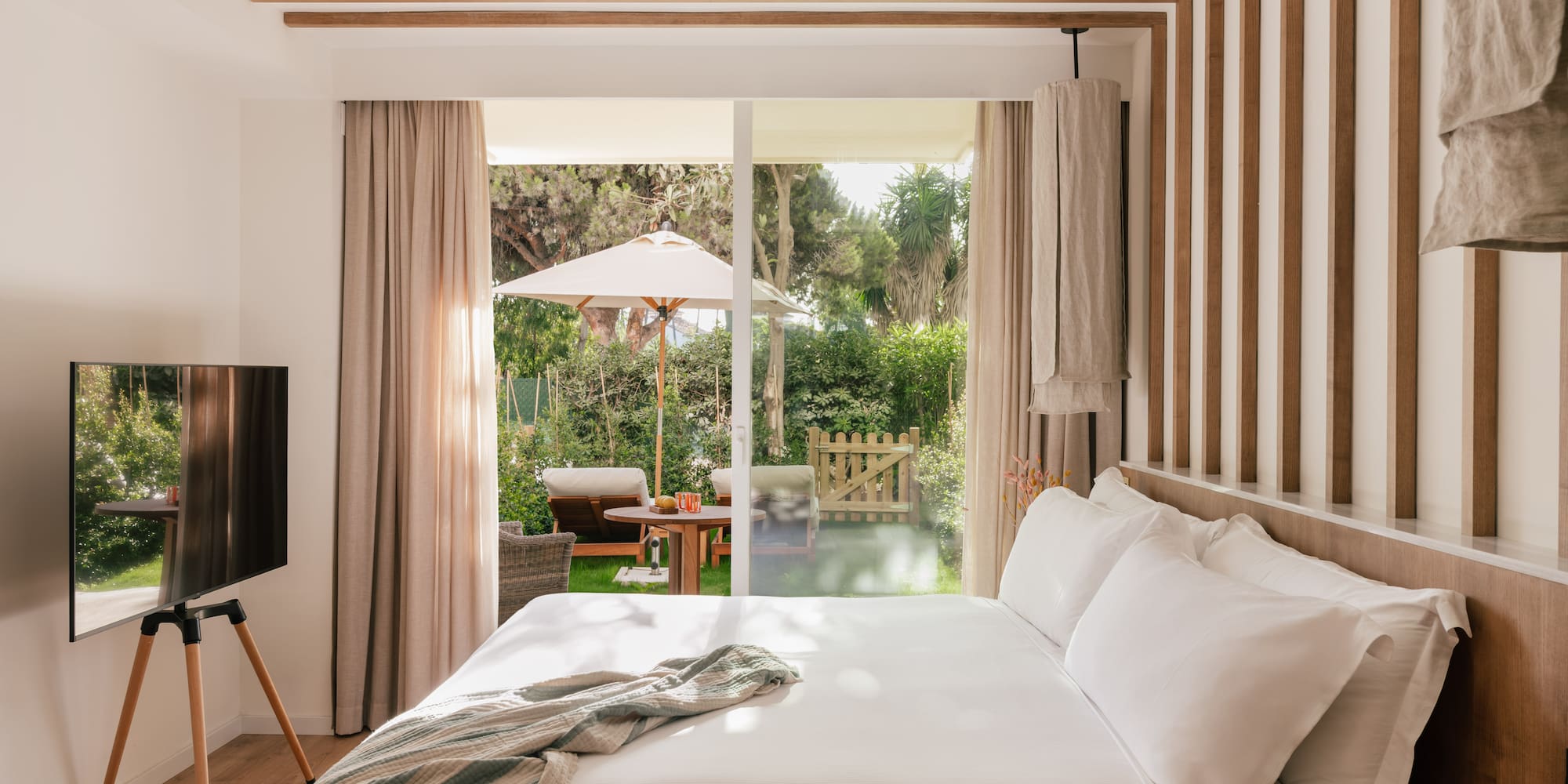 a bed with a television in a room with a patio and trees