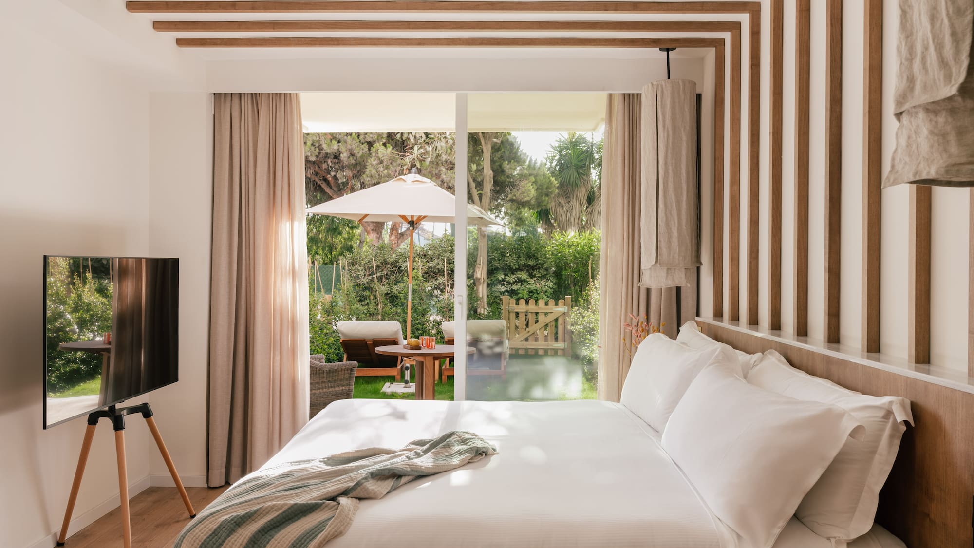 a bed with a television in a room with a patio and trees