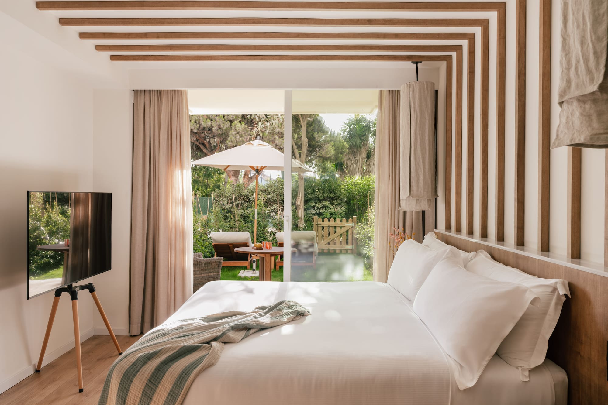 a bed with a television in a room with a patio and trees