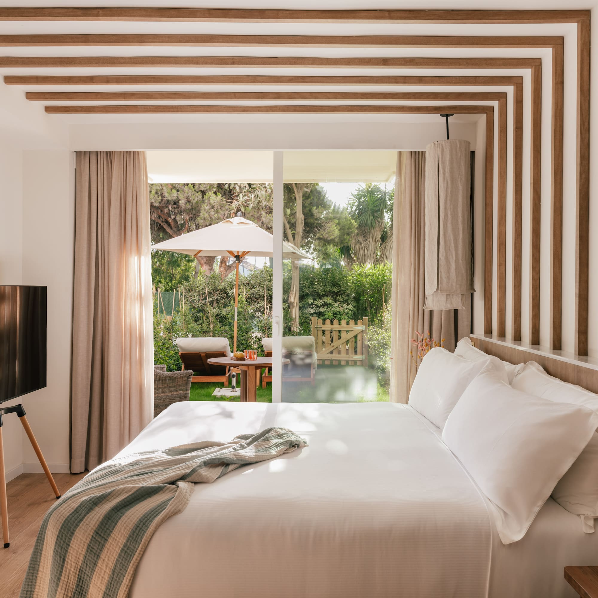 a bed with a television in a room with a patio and trees