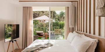 a bed with a television in a room with a patio and trees