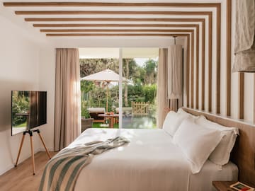 a bed with a television in a room with a patio and trees