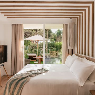 a bed with a television in a room with a patio and trees