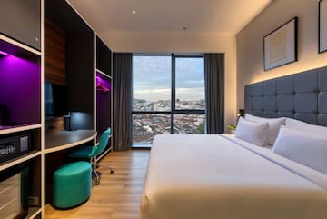 a room with a large bed and a desk and a window