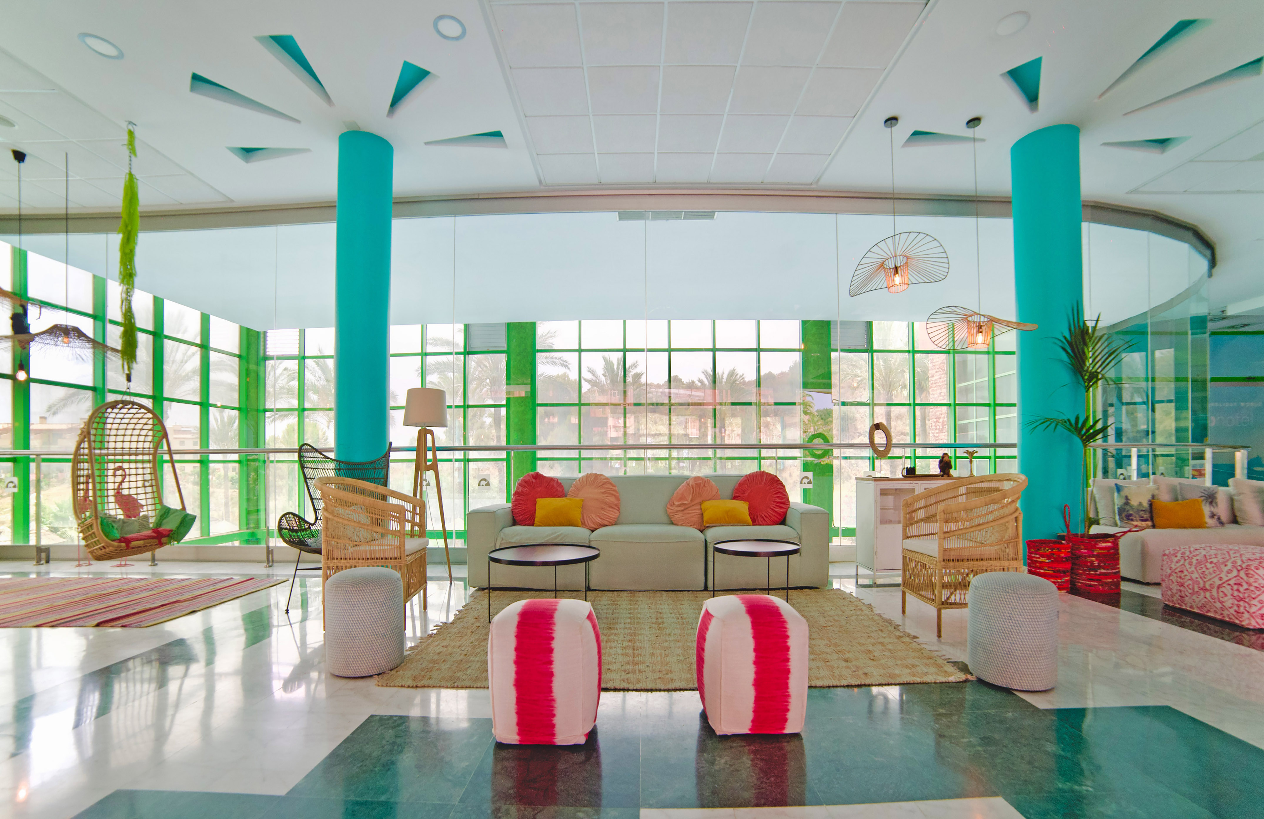 Colorful modern hotel lobby with rattan furniture, turquoise columns.