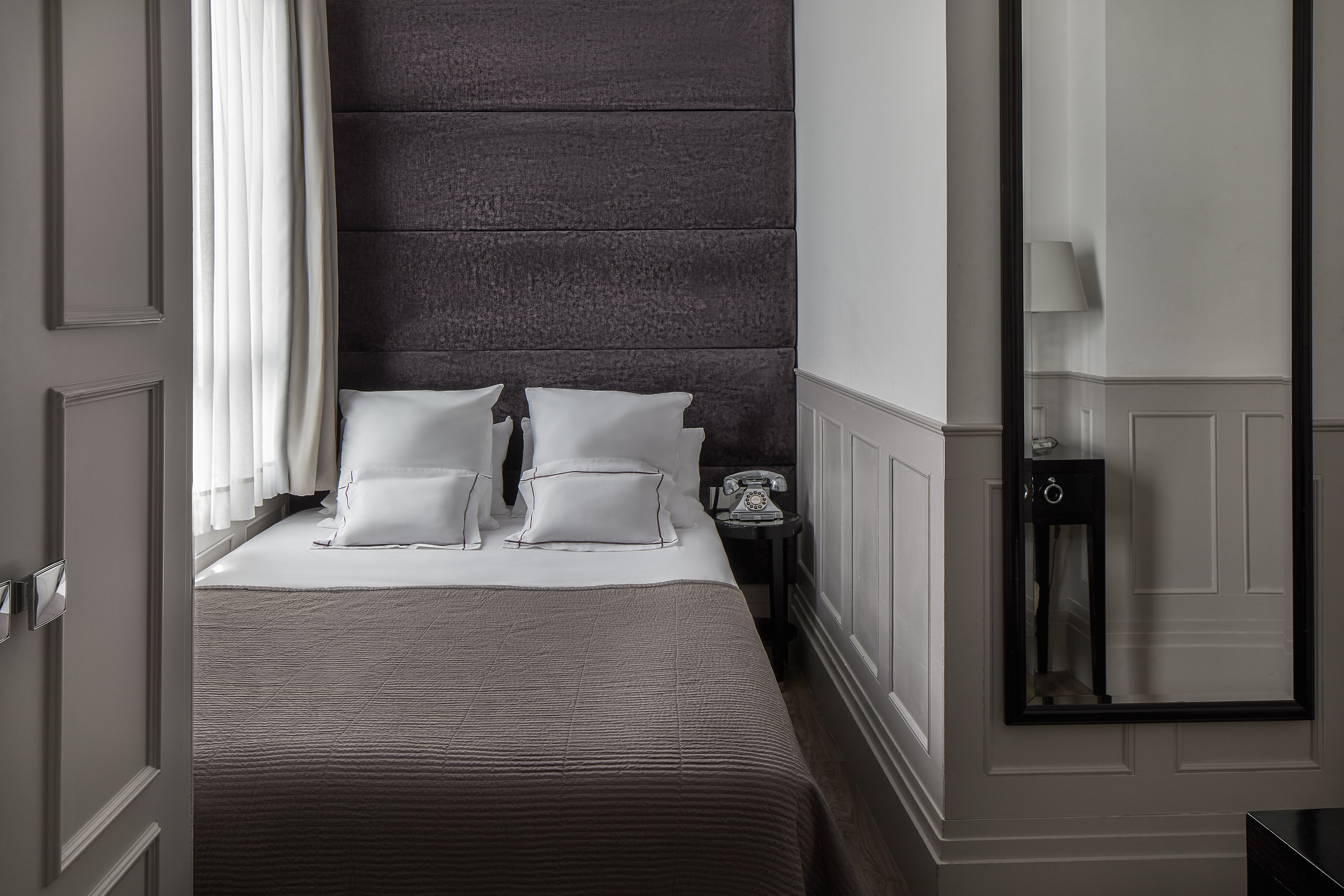 a bed with pillows and a mirror in the background