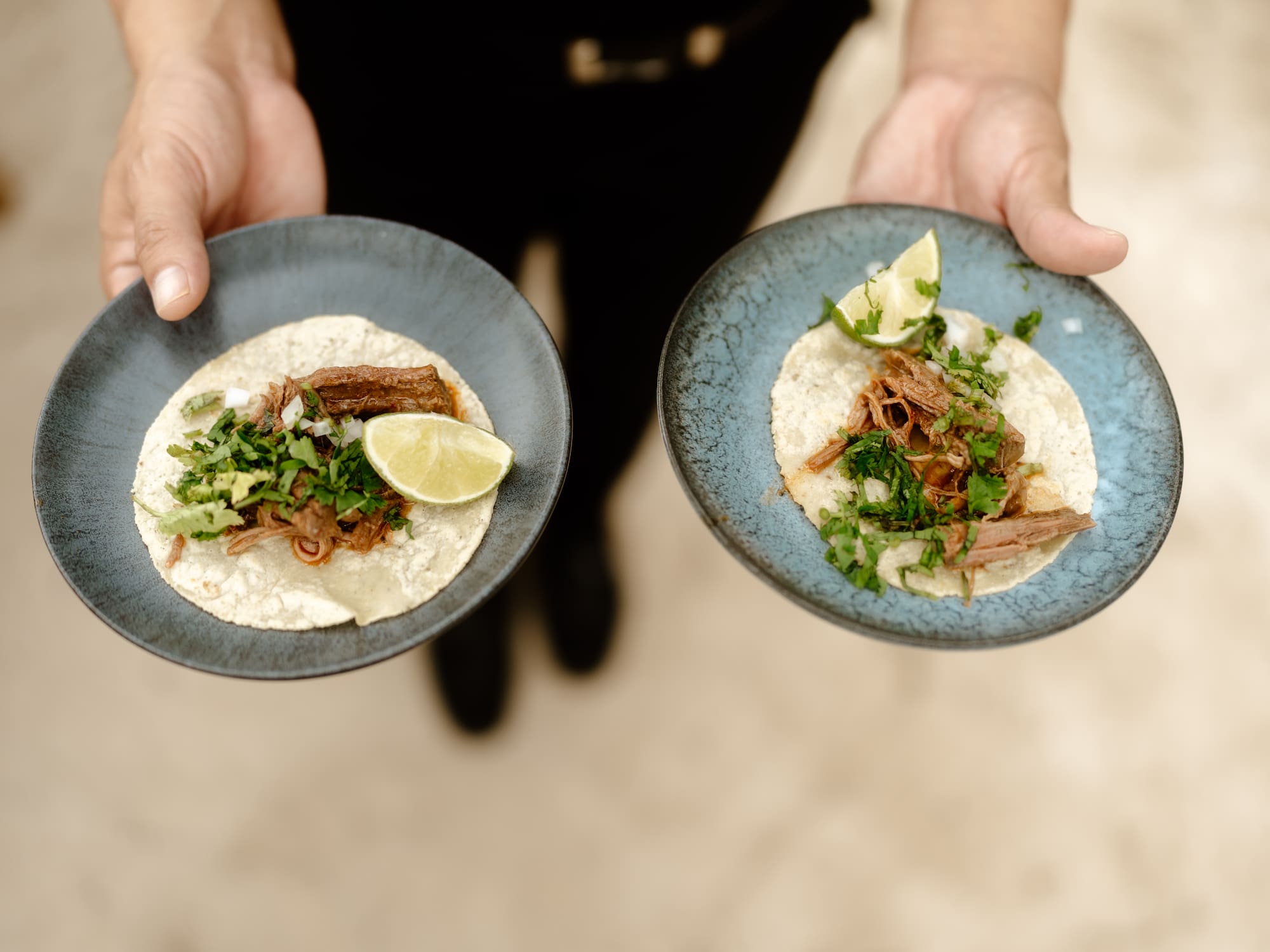 a person holding plates of tacos