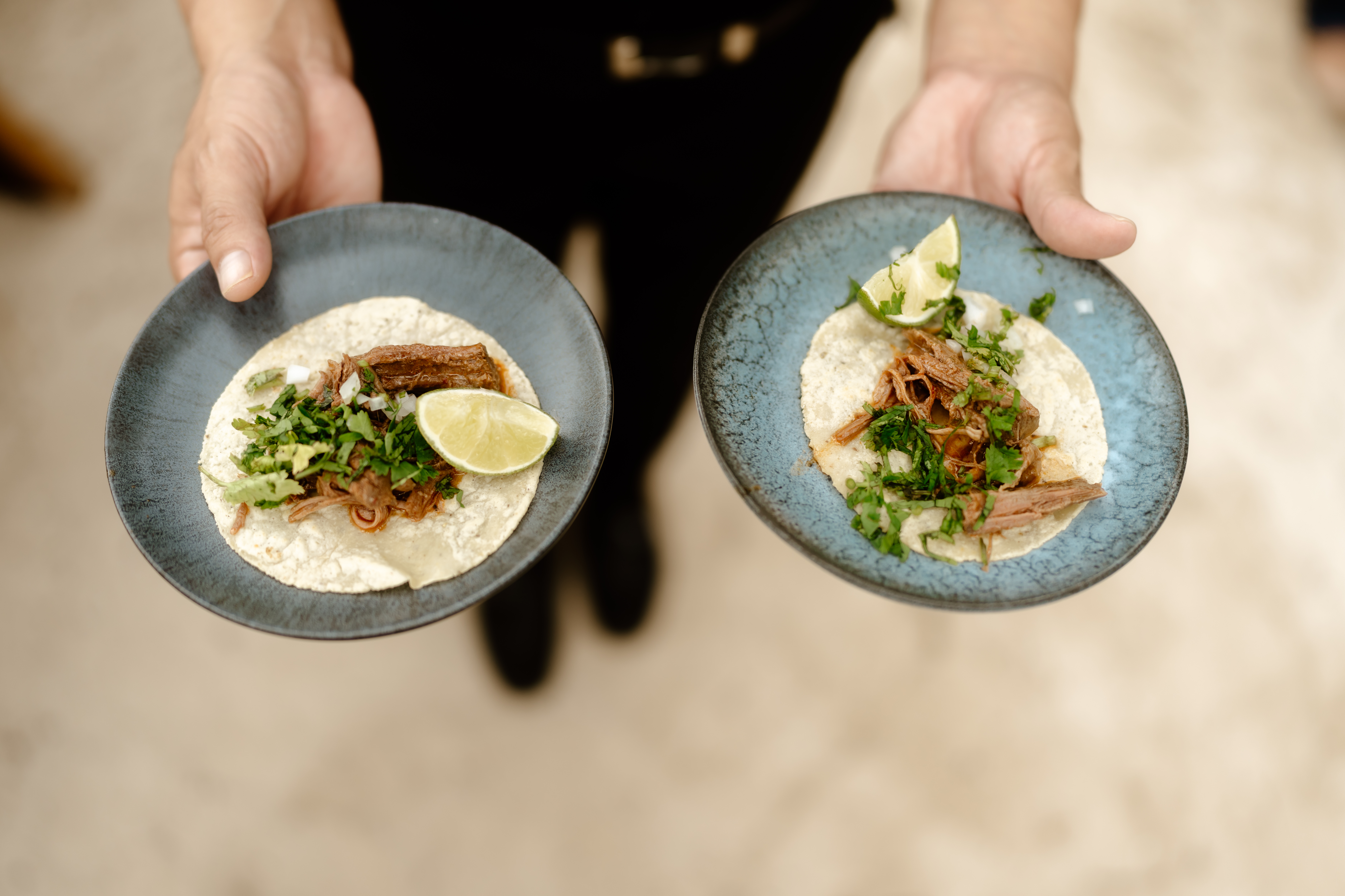 a person holding plates of tacos