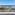 Coastal resort ocean view with sandy beach, marina, hotels, and blue sky.