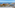 Coastal resort ocean view with sandy beach, marina, hotels, and blue sky.