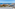 Coastal resort ocean view with sandy beach, marina, hotels, and blue sky.