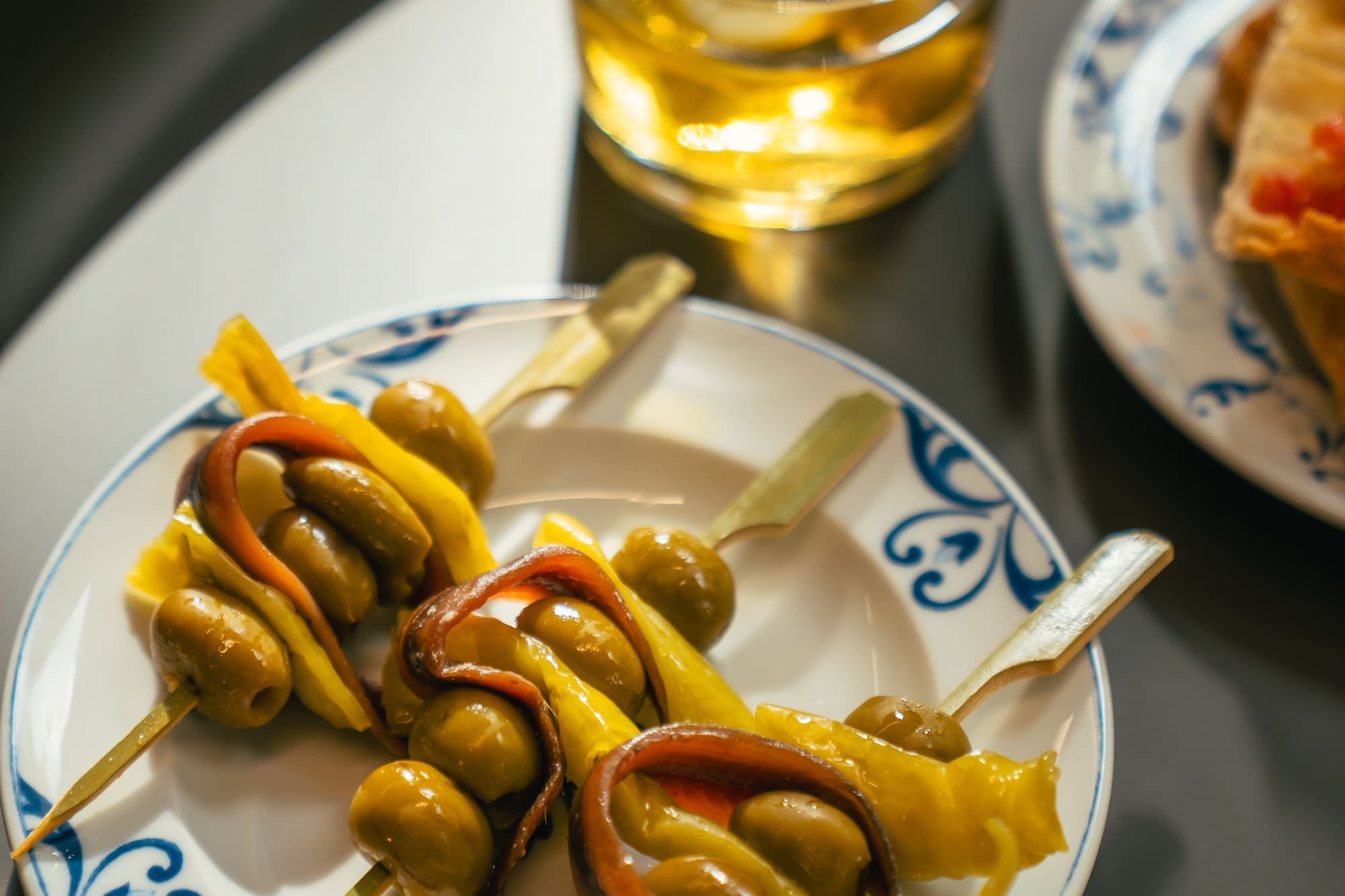 Gilda skewers of olives, anchovies, peppers, beside a cocktail.
