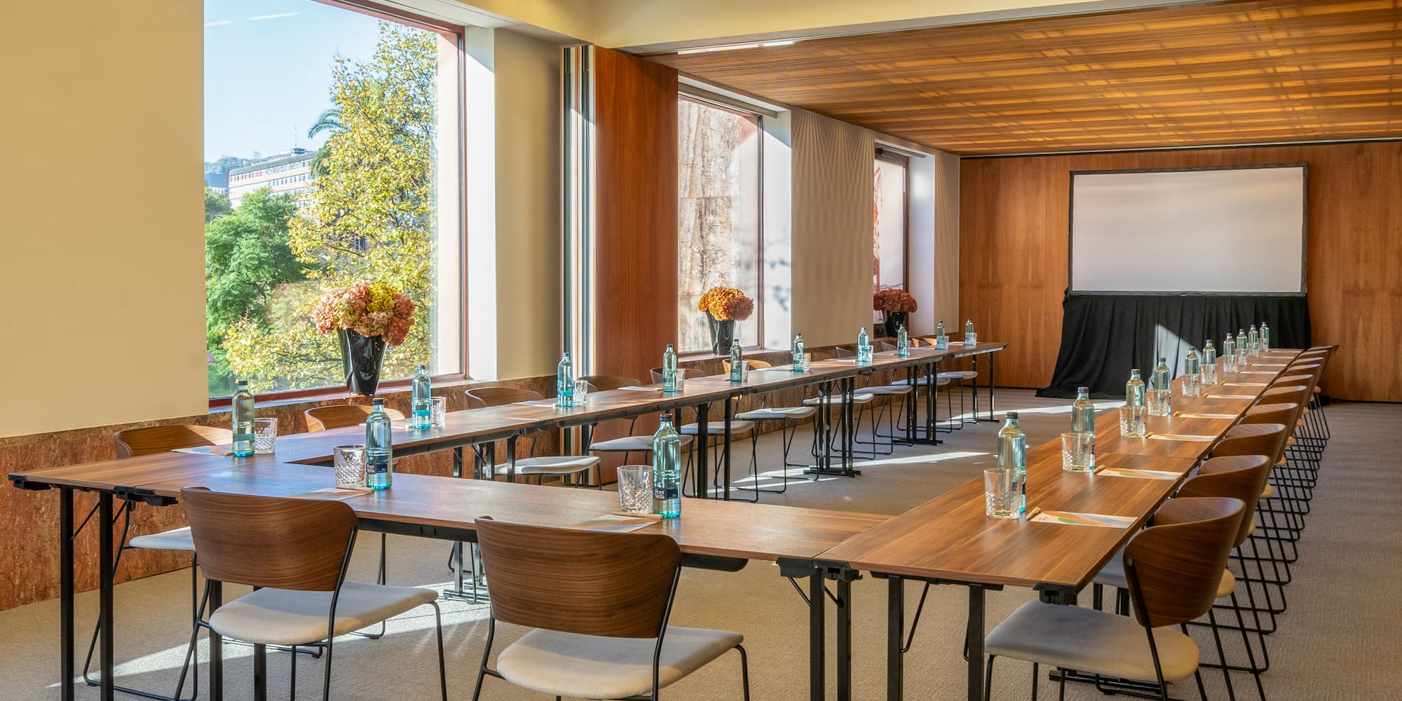 a room with tables and chairs and a screen