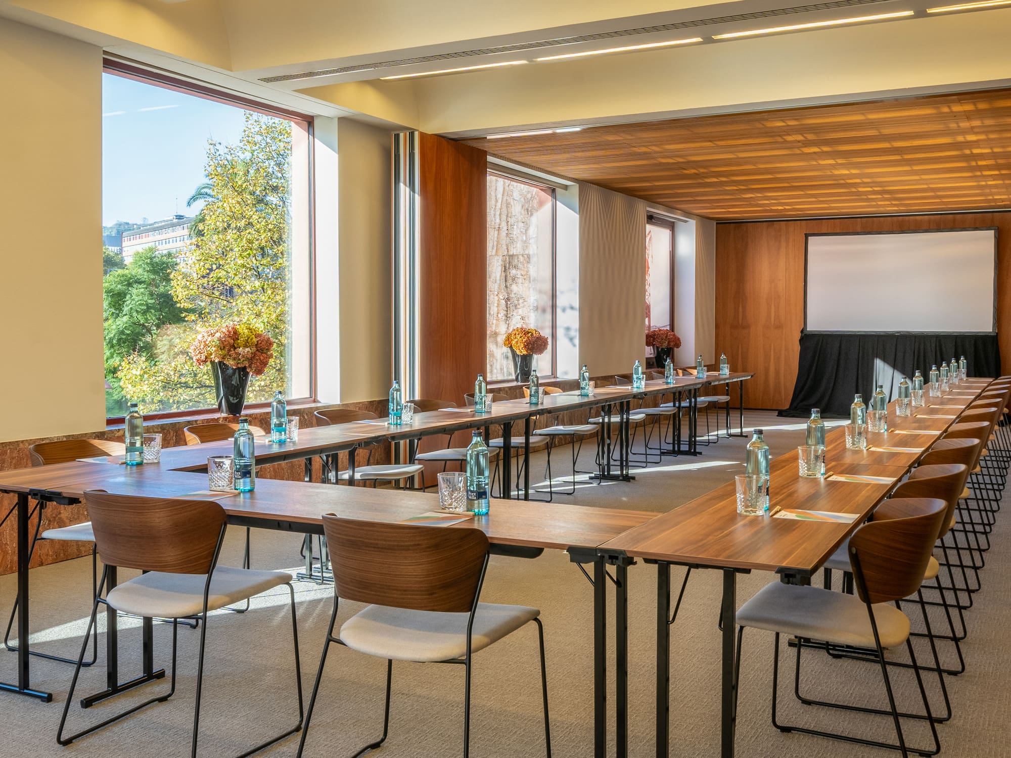 a room with tables and chairs and a screen