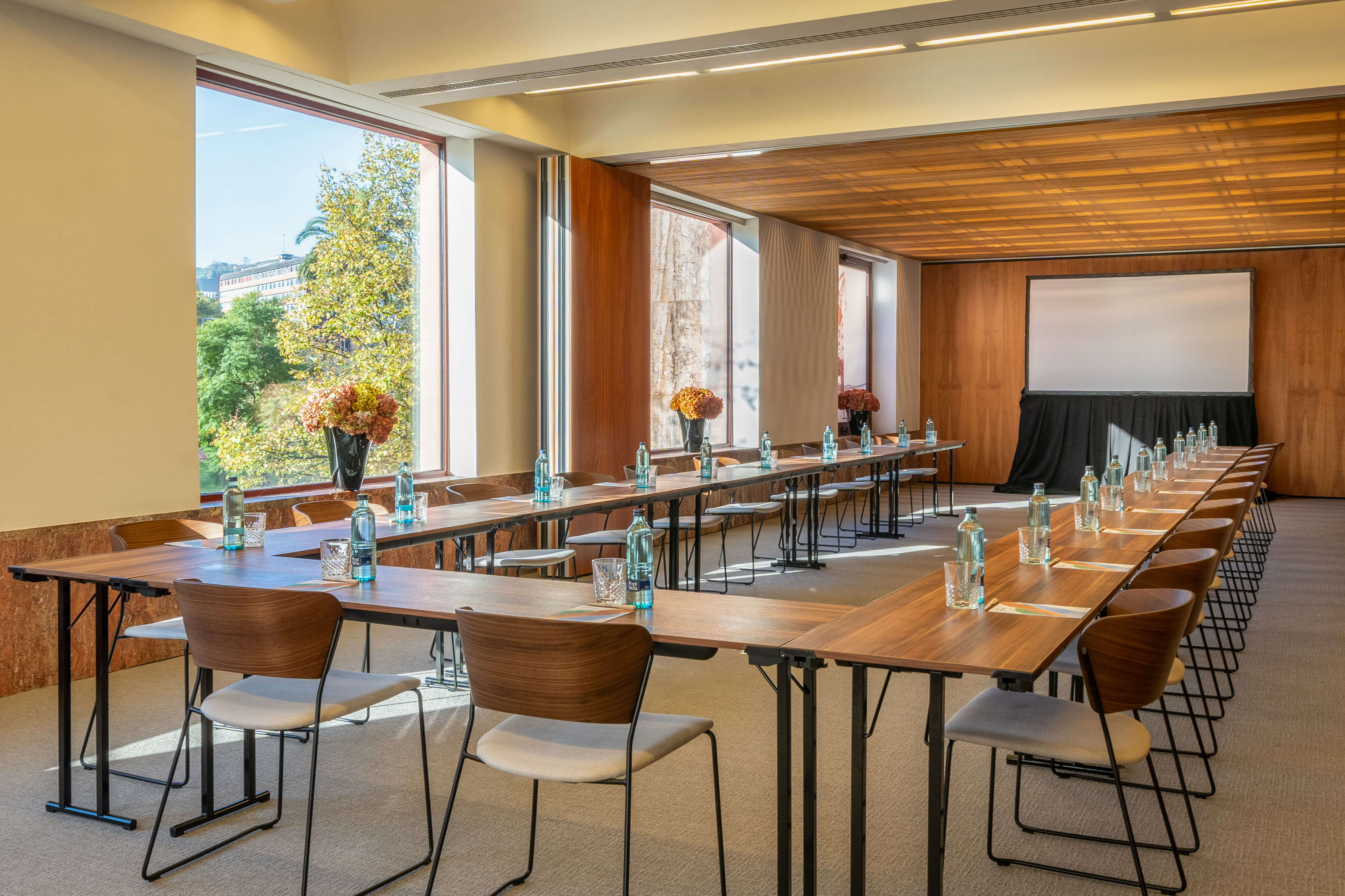 a room with tables and chairs and a screen