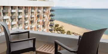 a balcony with chairs and a beach view