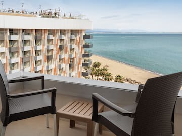 a balcony with chairs and a beach view