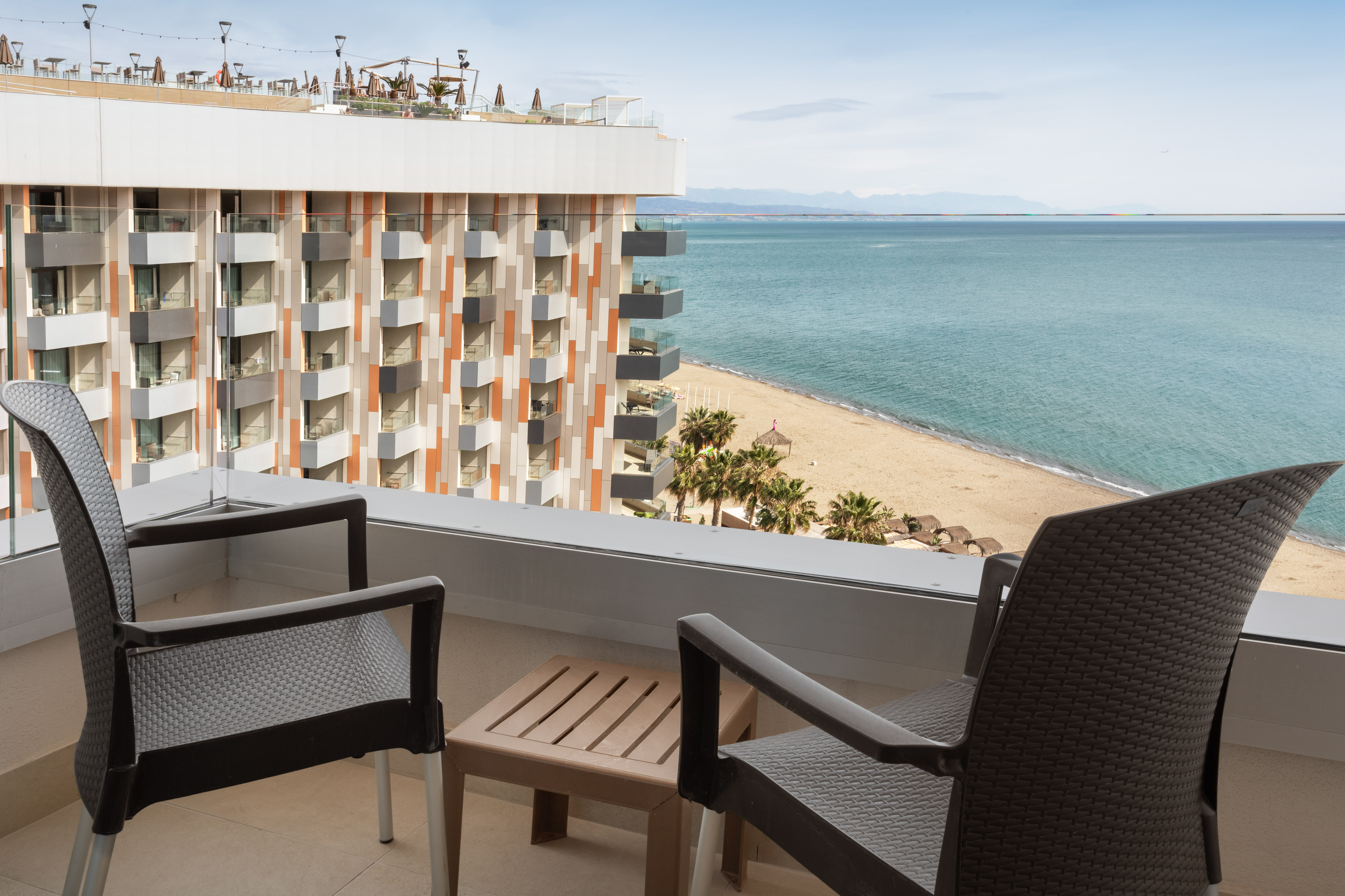 a balcony with chairs and a beach view