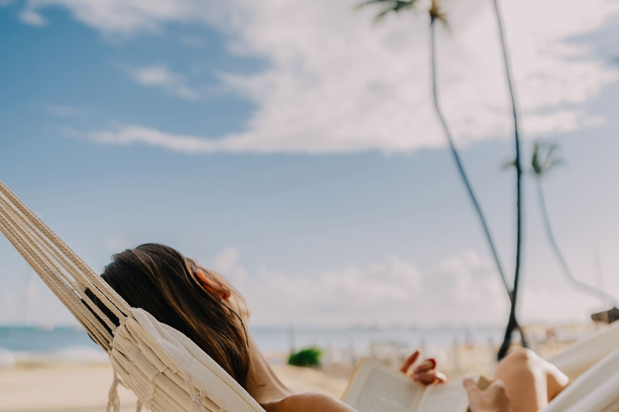a woman lying in a hammock on a beach