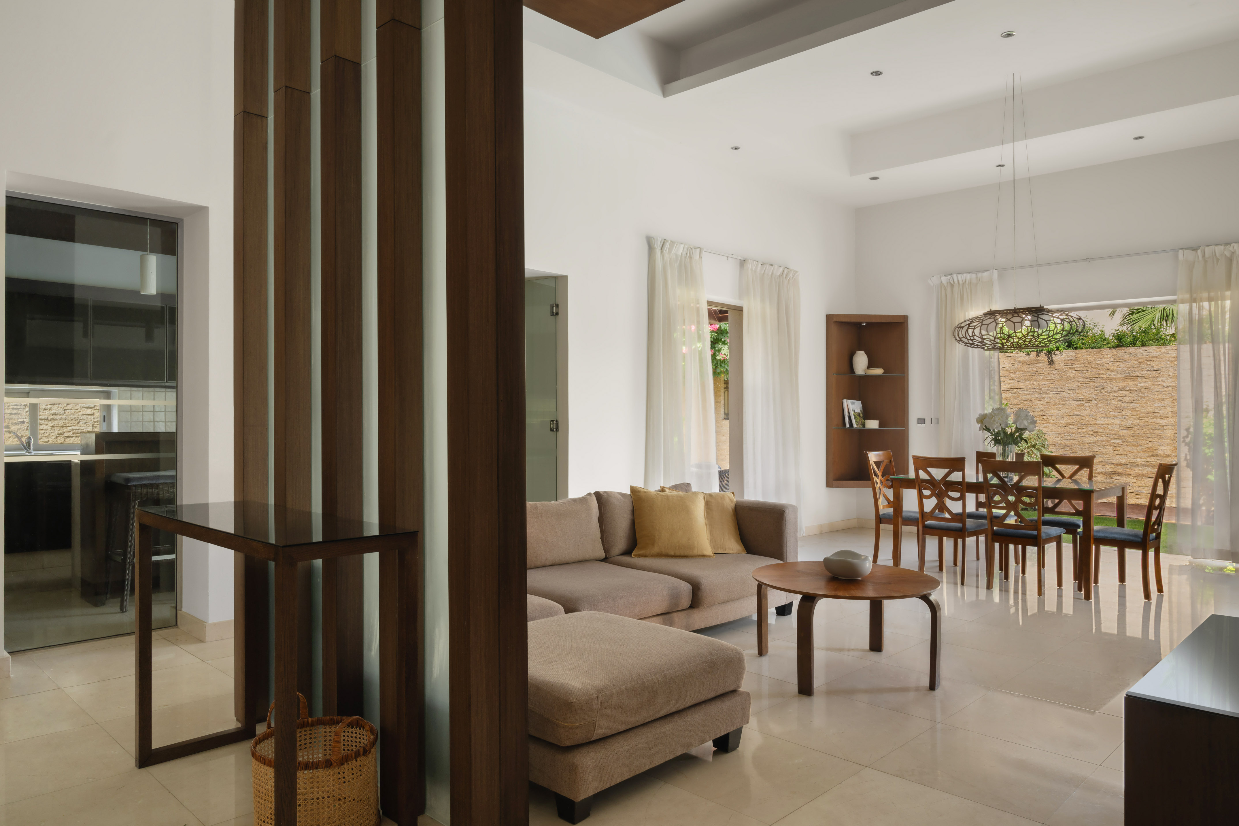 Modern open-plan living room with sectional sofa, wooden dining set.