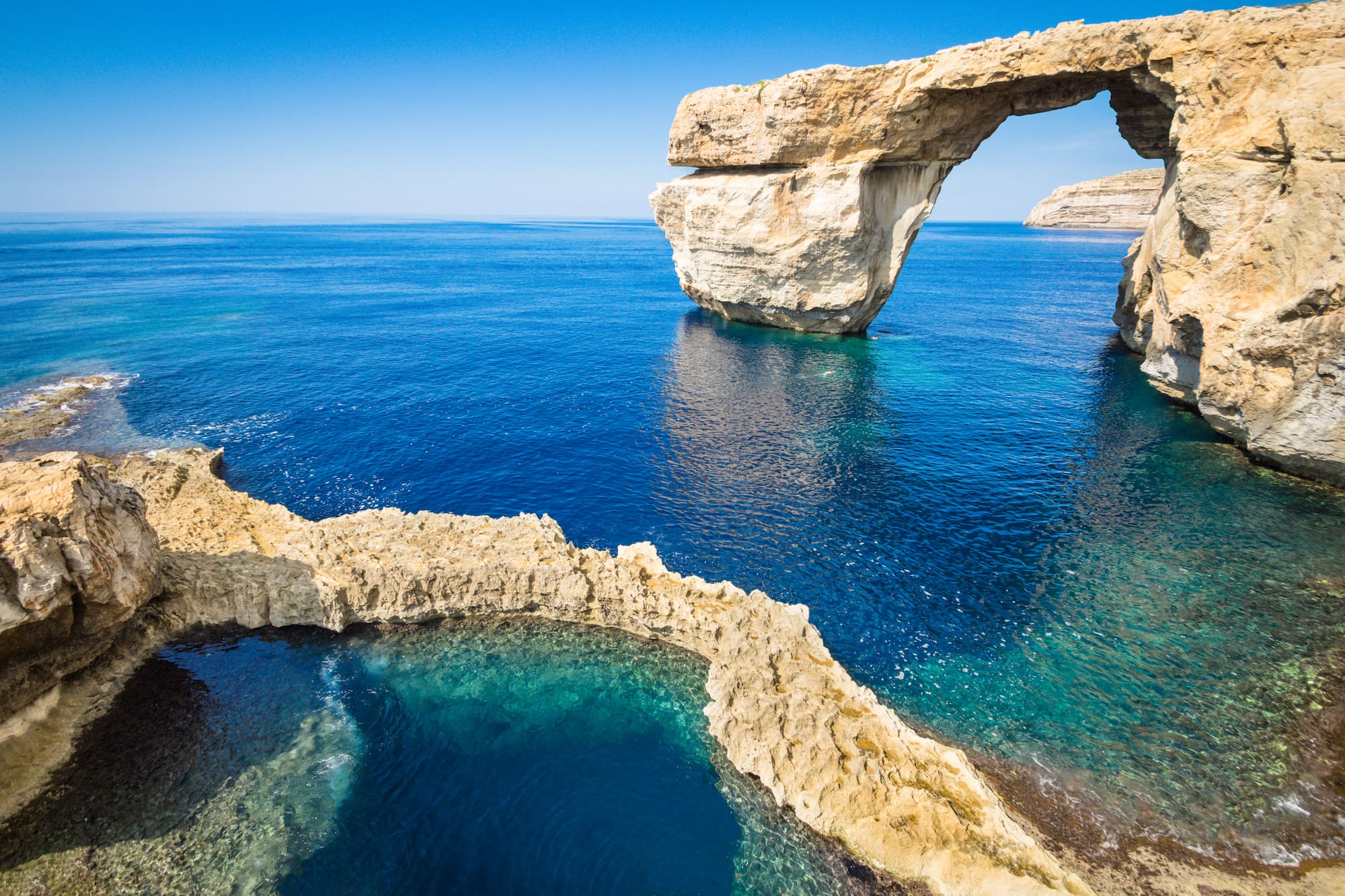 Azure Window natural rock arch over clear blue sea and rugged coastline.